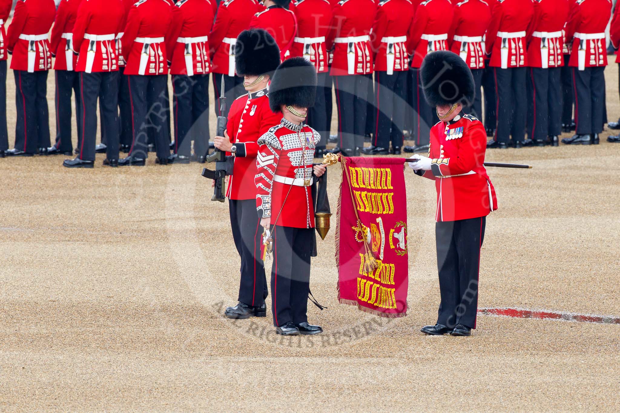 Trooping the Colour 2011: The Colour Case has been removed from the Colour, and the Colour Sergeant Chris Millin, has unrolled the flag, whilst the Duty Drummer is holding the colour case, and the sentry is presenting arms..
Horse Guards Parade, Westminster,
London SW1,
Greater London,
United Kingdom,
on 11 June 2011 at 10:33, image #55