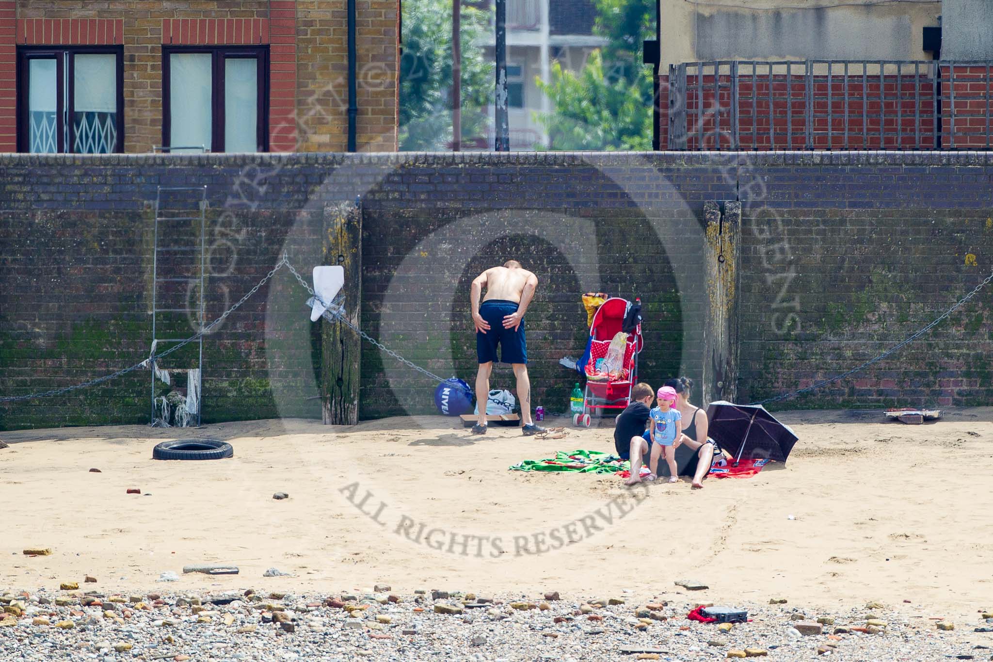 TOW River Thames Barge Driving Race 2013: Young family sunbathing on the beach of the River Thames..
River Thames between Greenwich and Westminster,
London,

United Kingdom,
on 13 July 2013 at 13:23, image #325