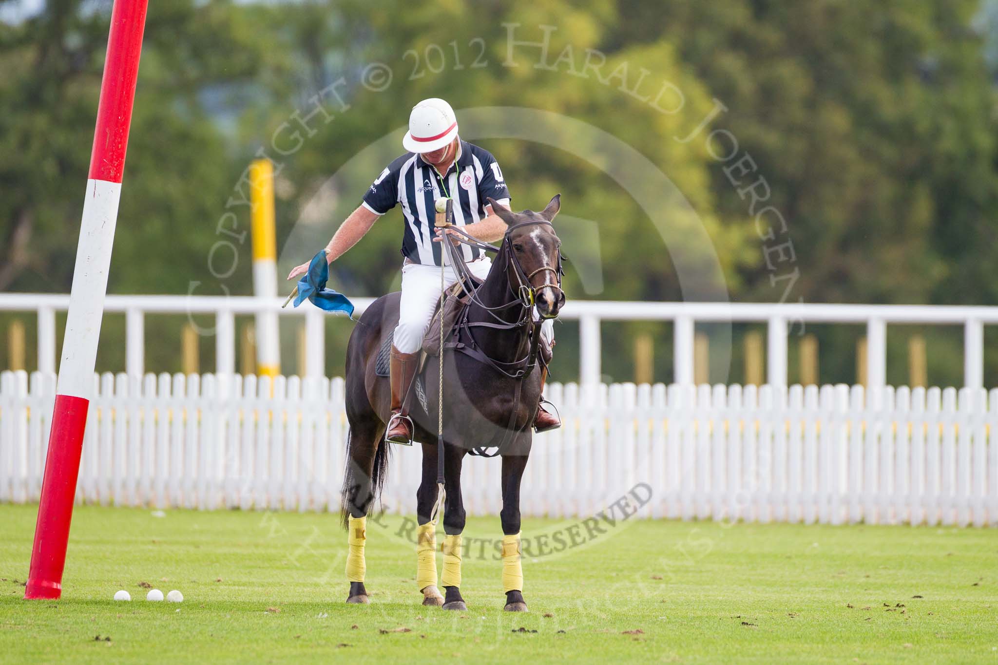 Photo 1209161002111D44630HaraldJoergens DBPC Polo in the Park 2012: The umpire and club polo manager Ian 'Ginger' Hunt, dropping a goal flags at one goal in preparation for the first match..
Dallas Burston Polo Club,
Stoneythorpe Estate,
Southam,
Warwickshire,
United Kingdom,
on 16 September 2012 at 10:02, image #24
