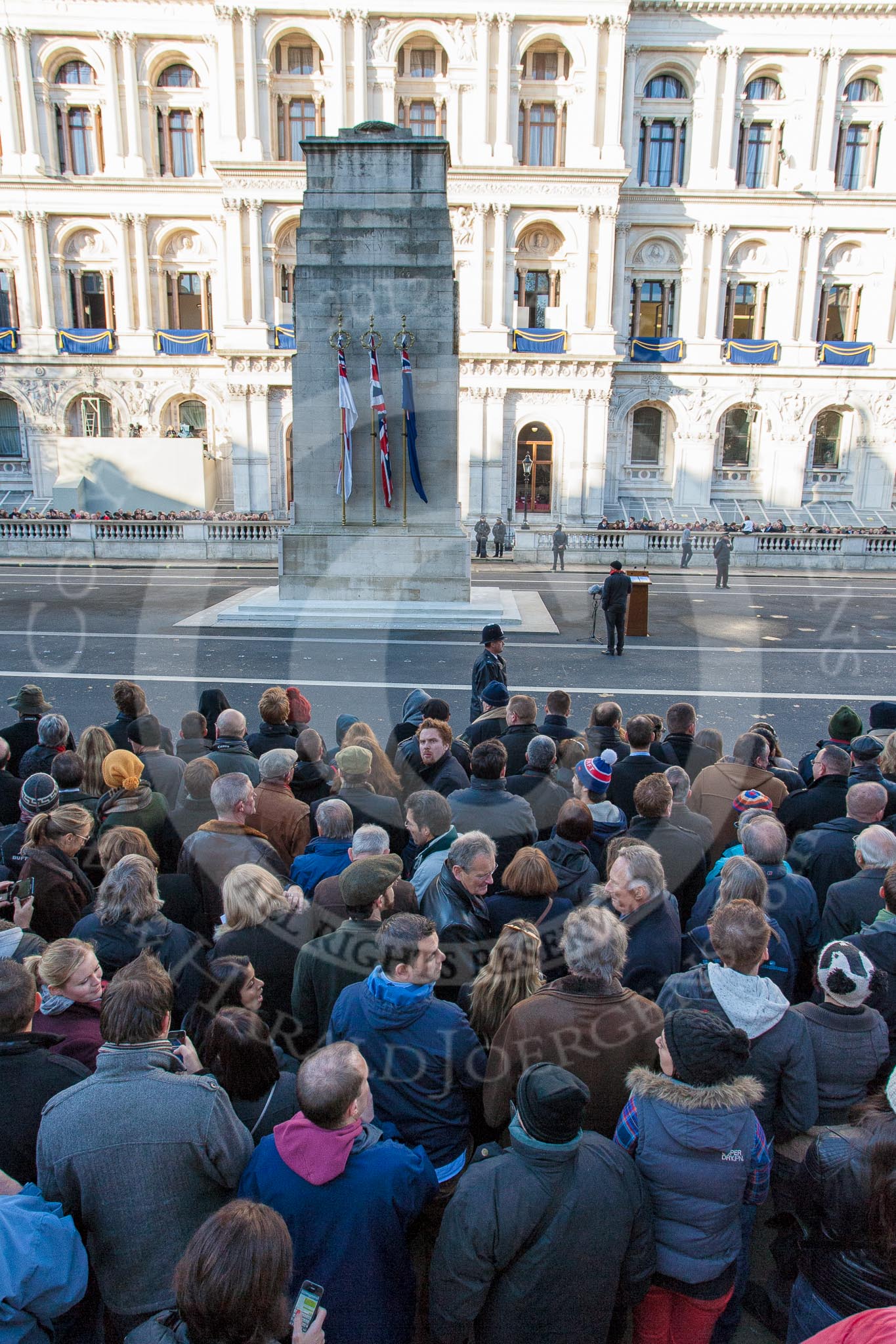 The Cenotaph, and the Foreign- and Commonwealth Office Building, in the morning of Remembrance Sunday. Large crowds have gathered on the pavement opposite.