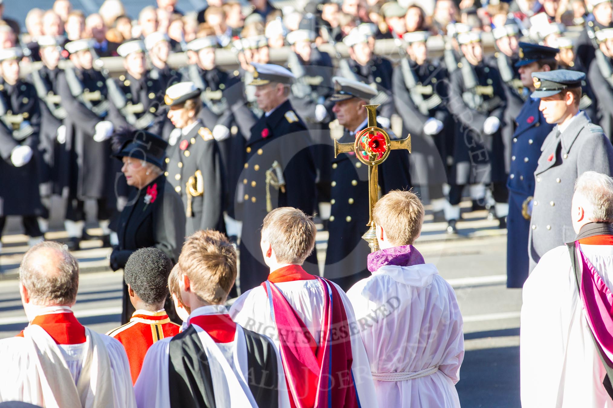 The choir boys and the golden cross with the red poppies, behind, and out of focus, HM The Queen and members of the Royal Family