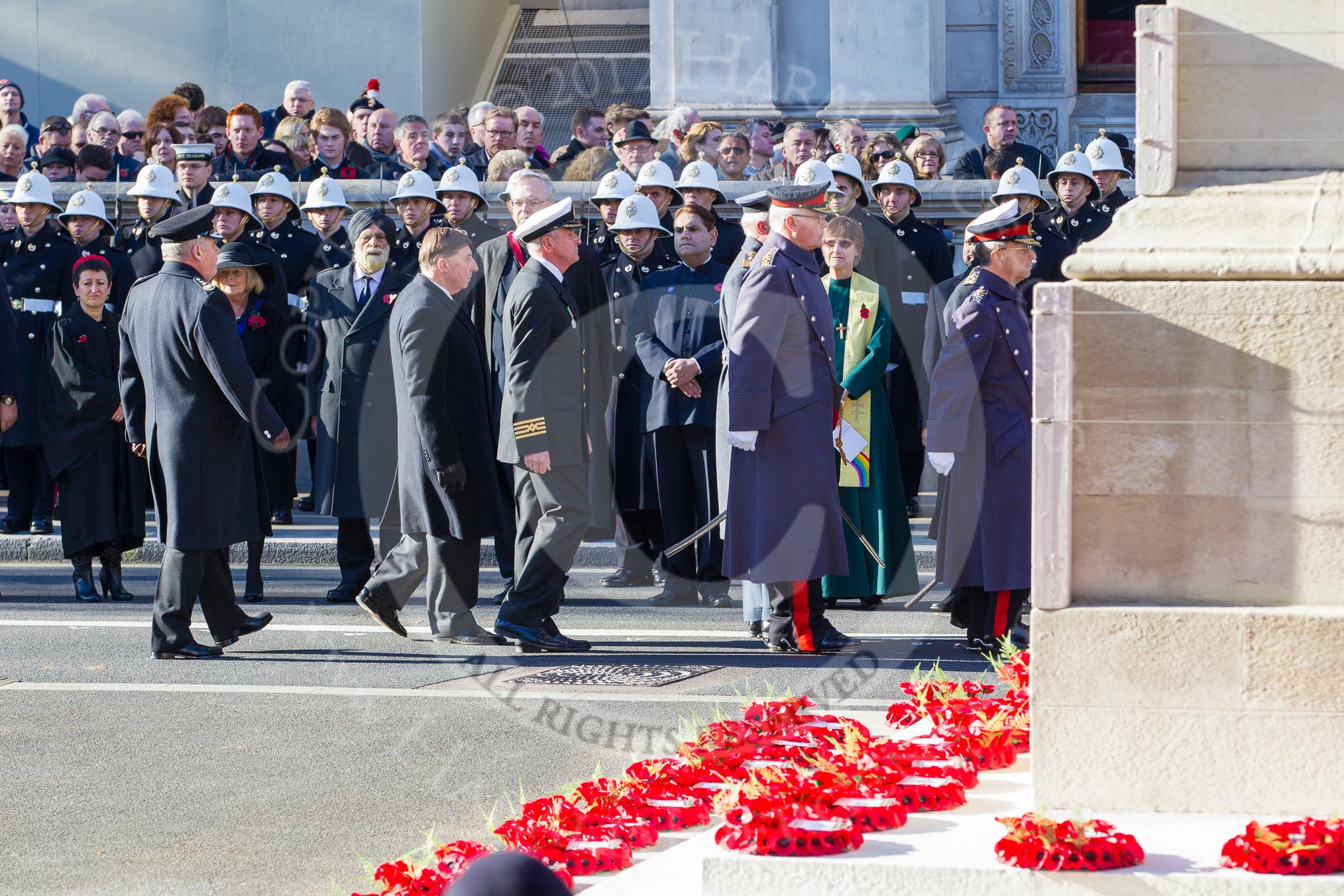 The four Chiefs of Staff of the Armed Forces and the chiefs of the civilian services about to leave Whitehall after the service, saluting at the Cenotaph. In the foreground the western side of the Cenotaph with the wreaths laid by the High Commissioners.