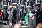 Commander Anne Sullivan, Royal Navy, handing, as Equerry, the wreath to HRH The Princess Royal. In the foreground, and out of focus, HM The Queen.