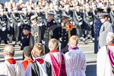 The choir boys and the golden cross with the red poppies, behind, and out of focus, HM The Queen and members of the Royal Family