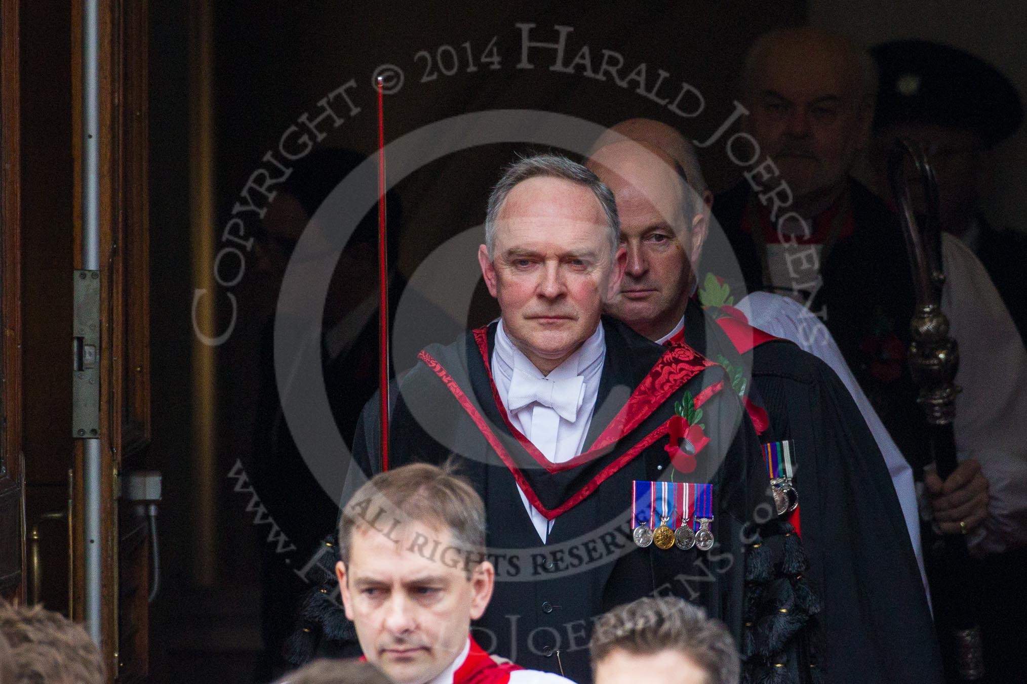Remembrance Sunday at the Cenotaph in London 2014: The Serjeant of the Vestry, David Baldin, leaving the Foreign- and Commonwealth Office, followed by the Chaplain General to Her Majesty’s Land Forces, the Sub-Dean of Her Majesty’s Chapels Royal, and the Dean of HM Chapels Royal, the Bishop of London.
Press stand opposite the Foreign Office building, Whitehall, London SW1,
London,
Greater London,
United Kingdom,
on 09 November 2014 at 10:53, image #99