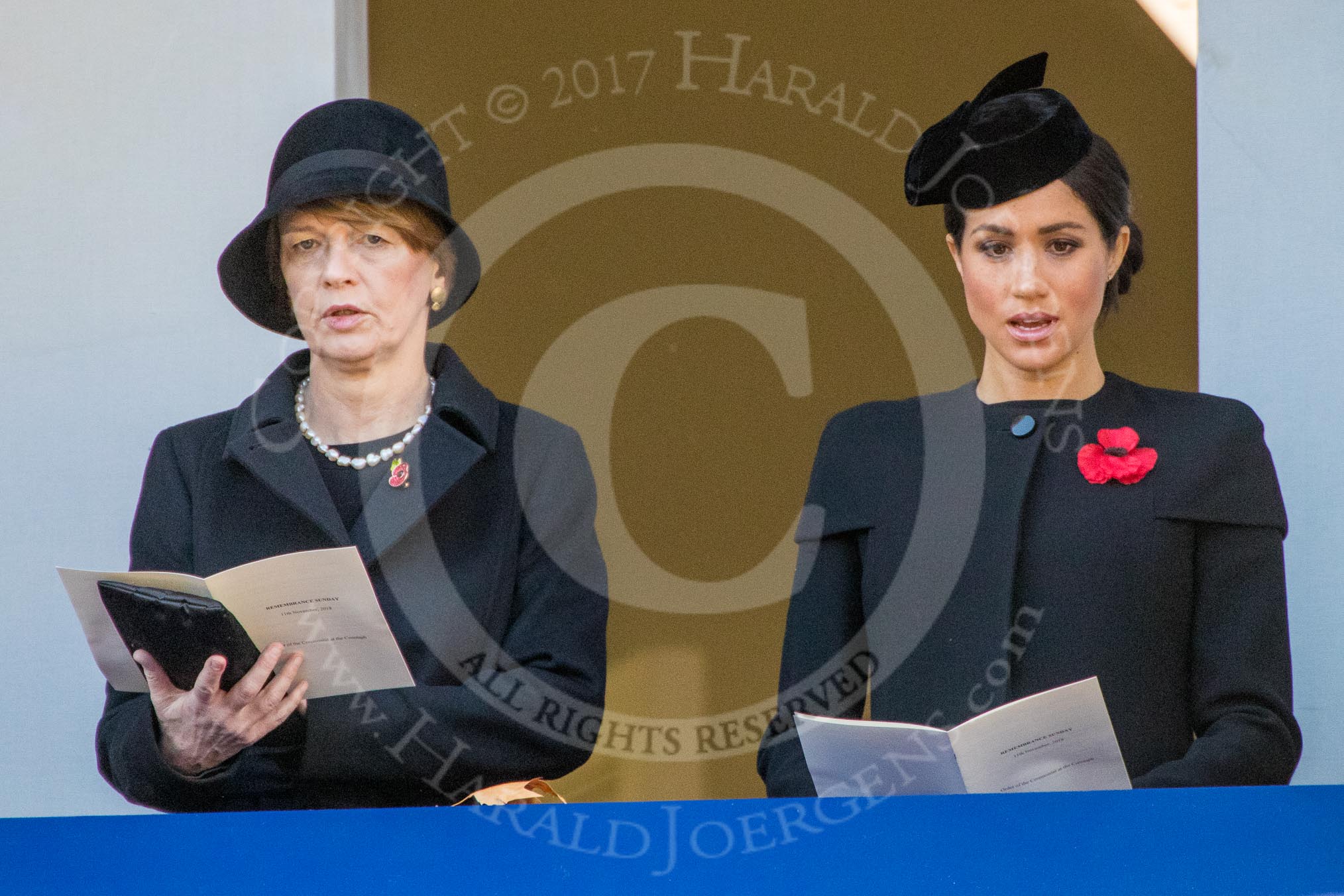 Mrs. Elke Büdenbender, wife of HE The President of the Federal Republic of Germany, Frank-Walter Steinmeier and HRH The Duchess of Sussex (Meghan), singing, on the balcony of the Foreign and Commonwealth Office during the Remembrance Sunday Cenotaph Ceremony 2018 at Horse Guards Parade, Westminster, London, 11 November 2018, 11:18.