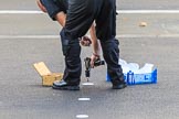 An Foreign and Commonwealth Office workman is screwing white discs onto the tarmac at Whitehall to mark the position of the members of the Royal Family and their Equerries before the  Remembrance Sunday Cenotaph Ceremony 2018 at Horse Guards Parade, Westminster, London, 11 November 2018, 08:54.