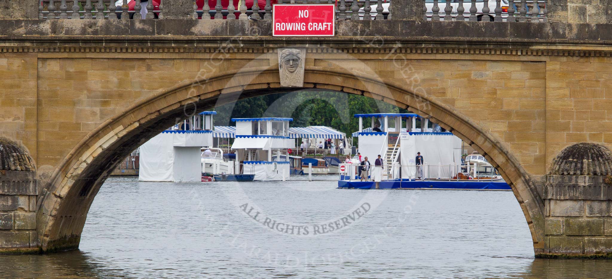 Henley Royal Regatta 2013 (Wednesday): Seen through the main arch of Henley Bridge (with a big red "No Rowing Craft" sign( the blue and white boxes near the finish line of the Henley Royal Regatta 2013..
River Thames between Henley and Temple Island,
Henley-on-Thames,
Berkshire,
United Kingdom,
on 03 July 2013 at 09:16, image #6
