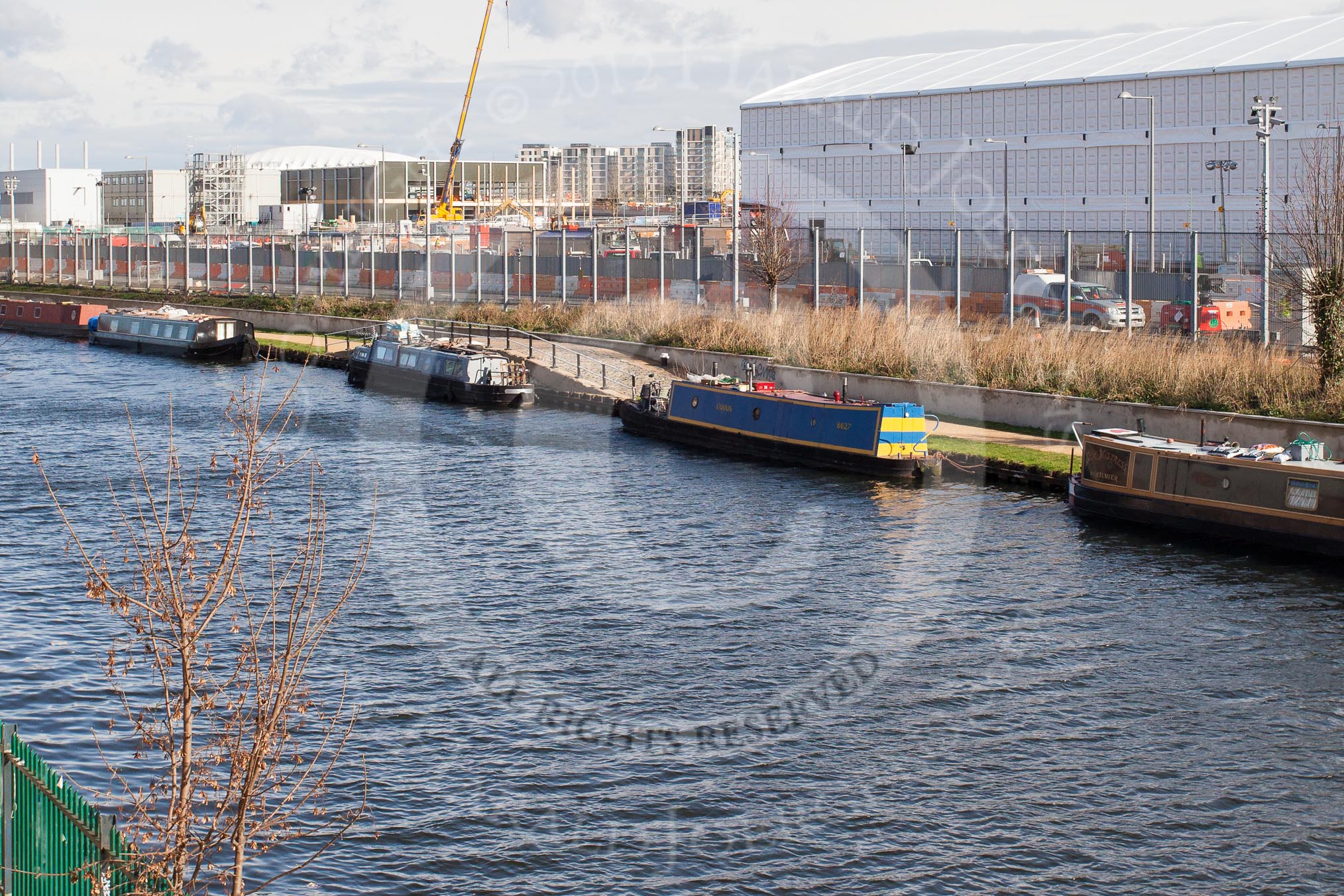 The Boat Race season 2012 - Crew Announcement and Weigh In: The River Lee seen from Forman's Fish Island. Behind the moored narrowboats the Olympic Park, with the Olympic Stadium on the right..
Forman's Fish Island,
London E3,

United Kingdom,
on 05 March 2012 at 10:43, image #58