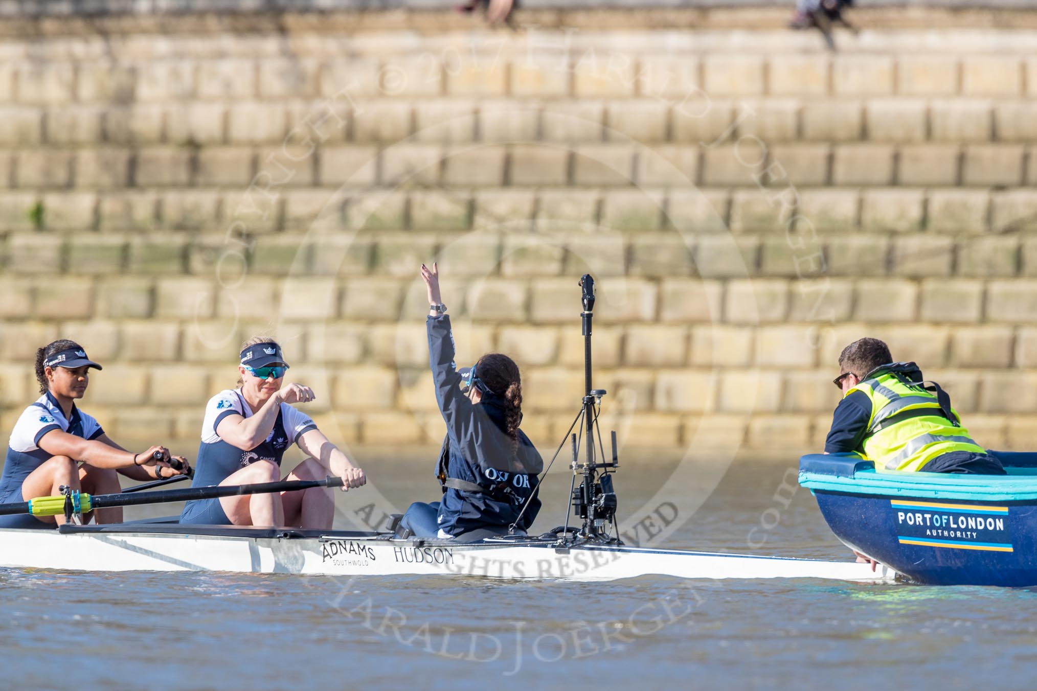 The Boat Race season 2017 -  The Cancer Research Women's Boat Race: The Oxford eight at the stake boat 7 Jenna Hebert, stroke Emily Cameron, cox Eleanor Shearer), Eleanor Shearer indicating that they are not ready yet.
River Thames between Putney Bridge and Mortlake,
London SW15,

United Kingdom,
on 02 April 2017 at 16:34, image #118