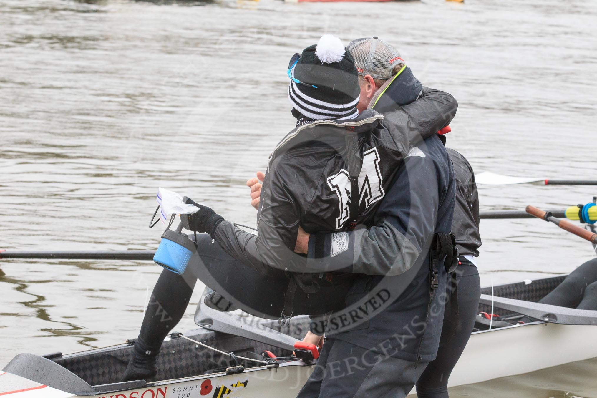 The Women's Boat Race season 2018 - fixture OUWBC vs. Molesey BC: Molesey cox Ella Taylor being carried to the boat by the MBC coach, much to the amusement of the crew.
River Thames between Putney Bridge and Mortlake,
London SW15,

United Kingdom,
on 04 March 2018 at 13:09, image #14