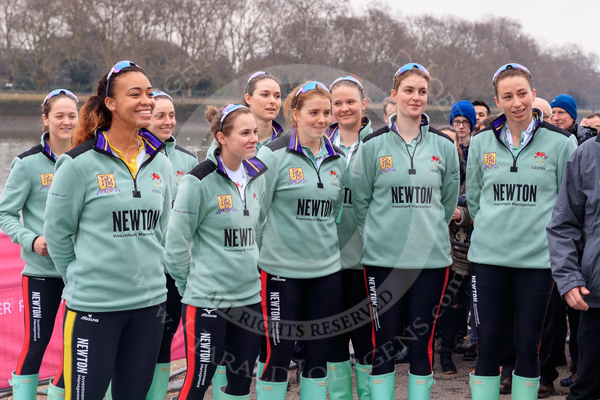 The Cancer Research UK Women's Boat Race 2018: The Cambridge crew  at the toss - president Daphne Martschenko (rowing in the reserve boat), cox Sophie Shapter, 6 Alice White, 7 Myriam Goudet-Boukhatmi, and in the second row 3 Kelsey Barolak, 4 Thea Zabell, and 5 Paula Wesselmann. On the right race umpire Sir Matthew Pinsent..
River Thames between Putney Bridge and Mortlake,
London SW15,

United Kingdom,
on 24 March 2018 at 14:41, image #49
