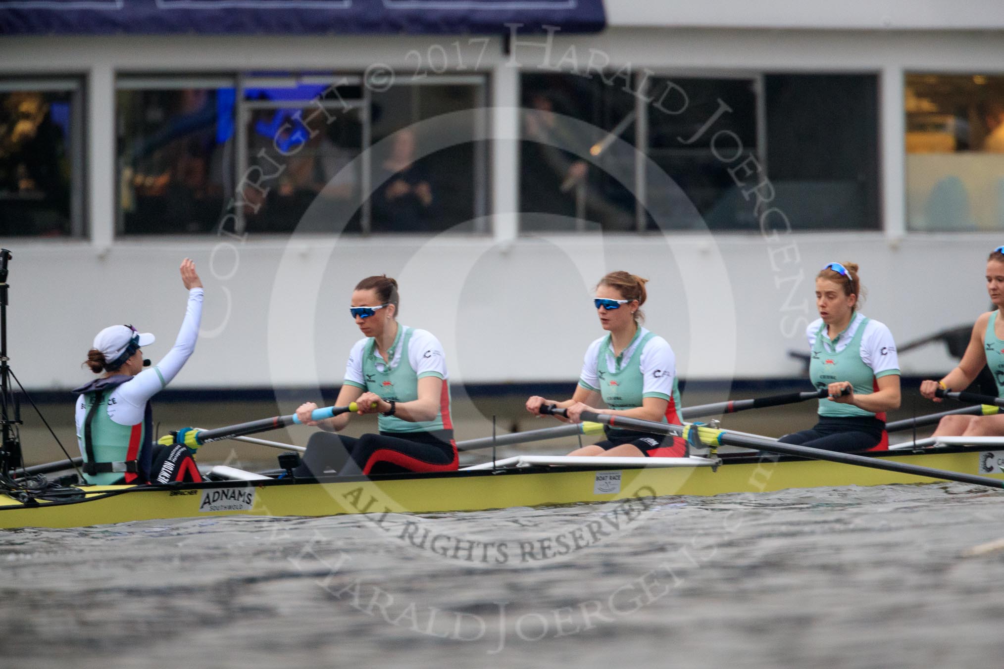 Photo 1803241628361X24457HaraldJoergens The Cancer Research UK Women's Boat Race 2018: The Cambridge Blue Boat just before the start of the race, with cox Sophie Shapter indicating with her raised hand that they are not ready yet. Here stroke Olivia Coffey, 7 Myriam Goudet-Boukhatmi, 6 Alice White, 5 Paula Wesselmann.
River Thames between Putney Bridge and Mortlake,
London SW15,
United Kingdom,
on 24 March 2018 at 16:28, image #158