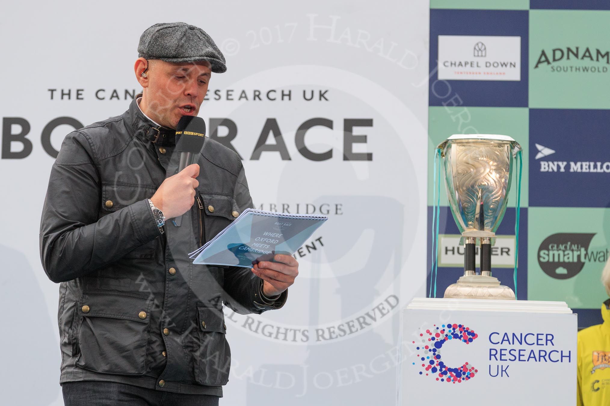The Cancer Research UK Women's Boat Race 2018: The BBC's Jason Mohammad. with the Women's Boat Race trophy.
River Thames between Putney Bridge and Mortlake,
London SW15,

United Kingdom,
on 24 March 2018 at 17:04, image #232