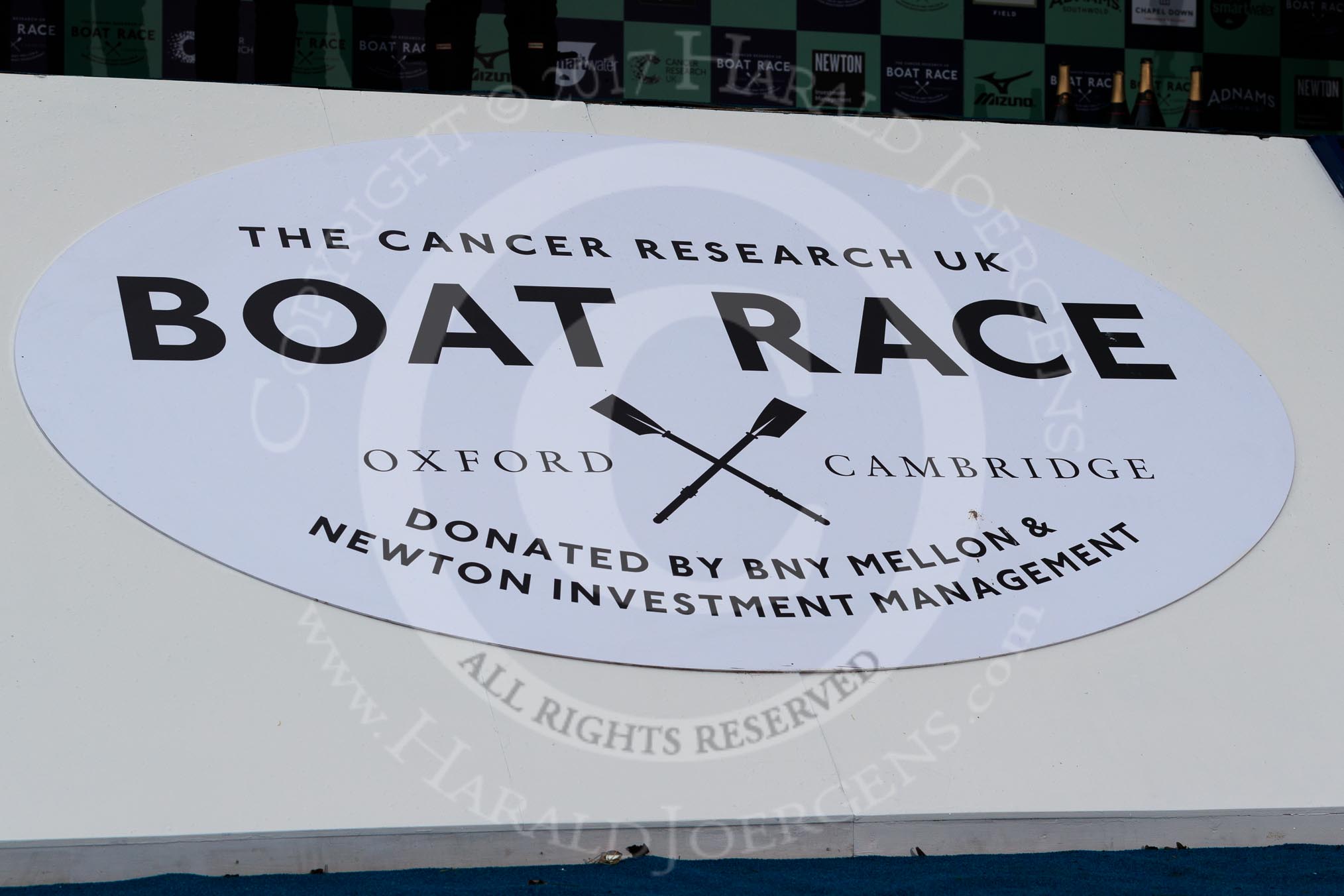 Photo 1803241705171X25195HaraldJoergens The Cancer Research UK Women's Boat Race 2018: The big sign at the podium for the Booat Race trophy presentation - "The Cancer Research UK Boat Race".
River Thames between Putney Bridge and Mortlake,
London SW15,
United Kingdom,
on 24 March 2018 at 17:05, image #235