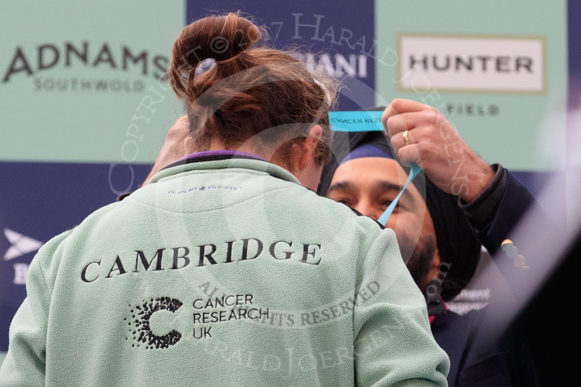 The Cancer Research UK Women's Boat Race 2018: Sir Harpal Kumar, CEO of Cancer Research UK. puts a Boat Race medal around the neck of Cambridge bow Tricia Smith.
River Thames between Putney Bridge and Mortlake,
London SW15,

United Kingdom,
on 24 March 2018 at 17:06, image #250