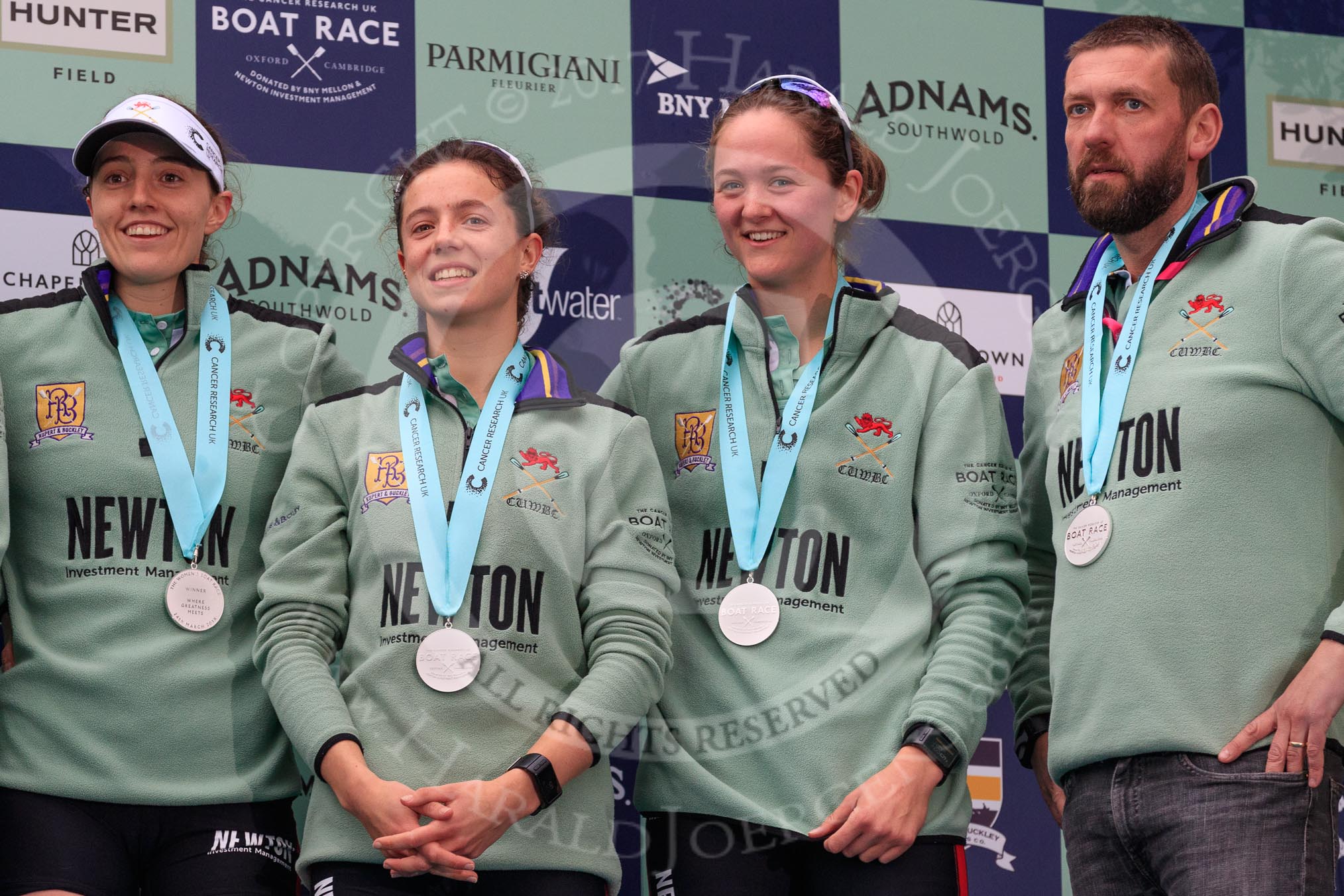 The Cancer Research UK Women's Boat Race 2018: Cambridge  3 seat Kelsey Barolak, 2 seat Imogen Grant, bow seat Tricia Smith, and CUWBC Head Coach Rob Baker with their Women's Boat Race medals. on the podium.
River Thames between Putney Bridge and Mortlake,
London SW15,

United Kingdom,
on 24 March 2018 at 17:08, image #273