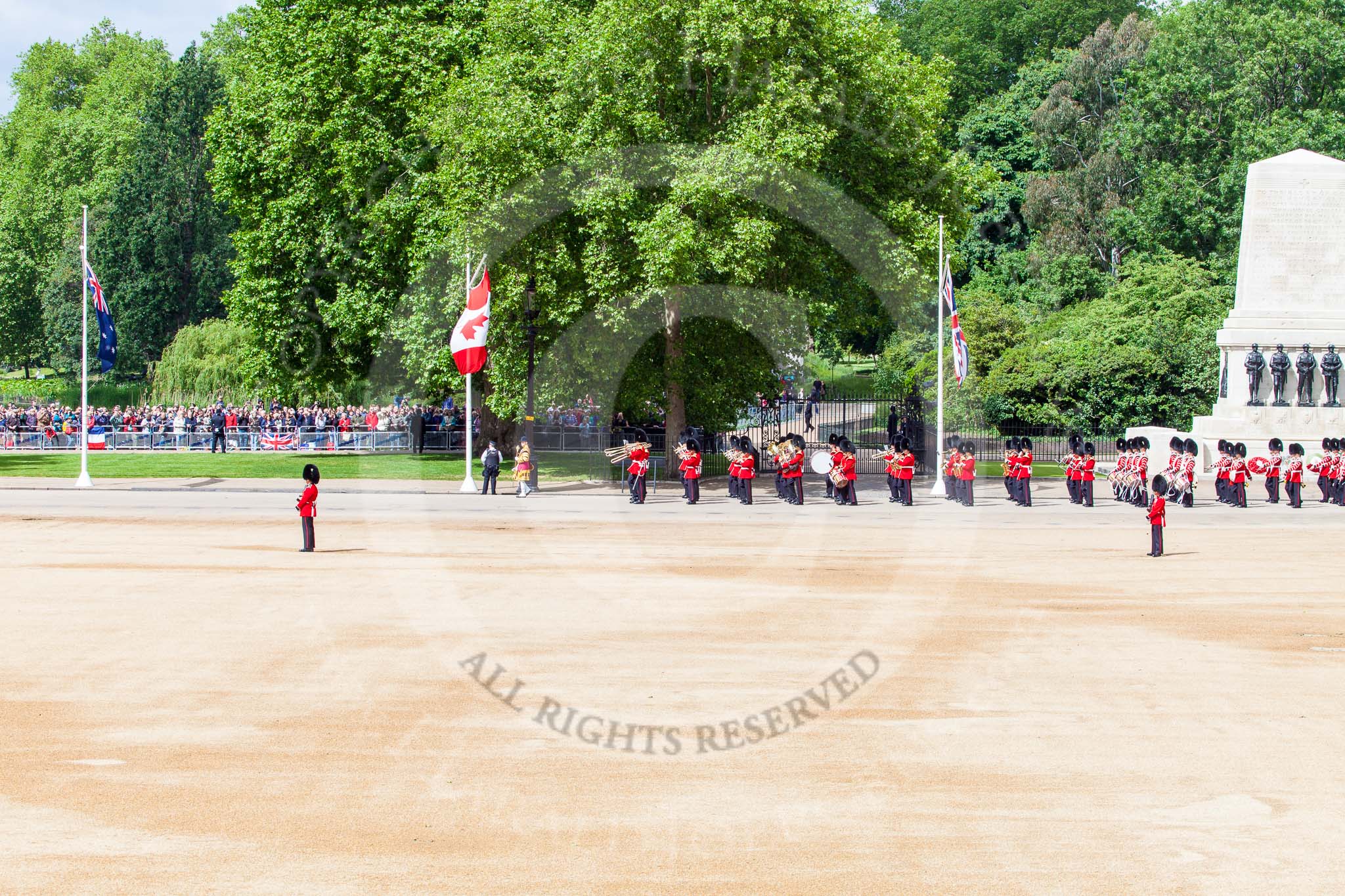Trooping the Colour 2013: A wide angle view of Horse Guards Parade - the Band of the Grenadier Guards is marching along St. James's Park, with the Guards Memorial on the right, and the lake, and lots of spectators, on the left. Image #93, 15 June 2013 10:28 Horse Guards Parade, London, UK