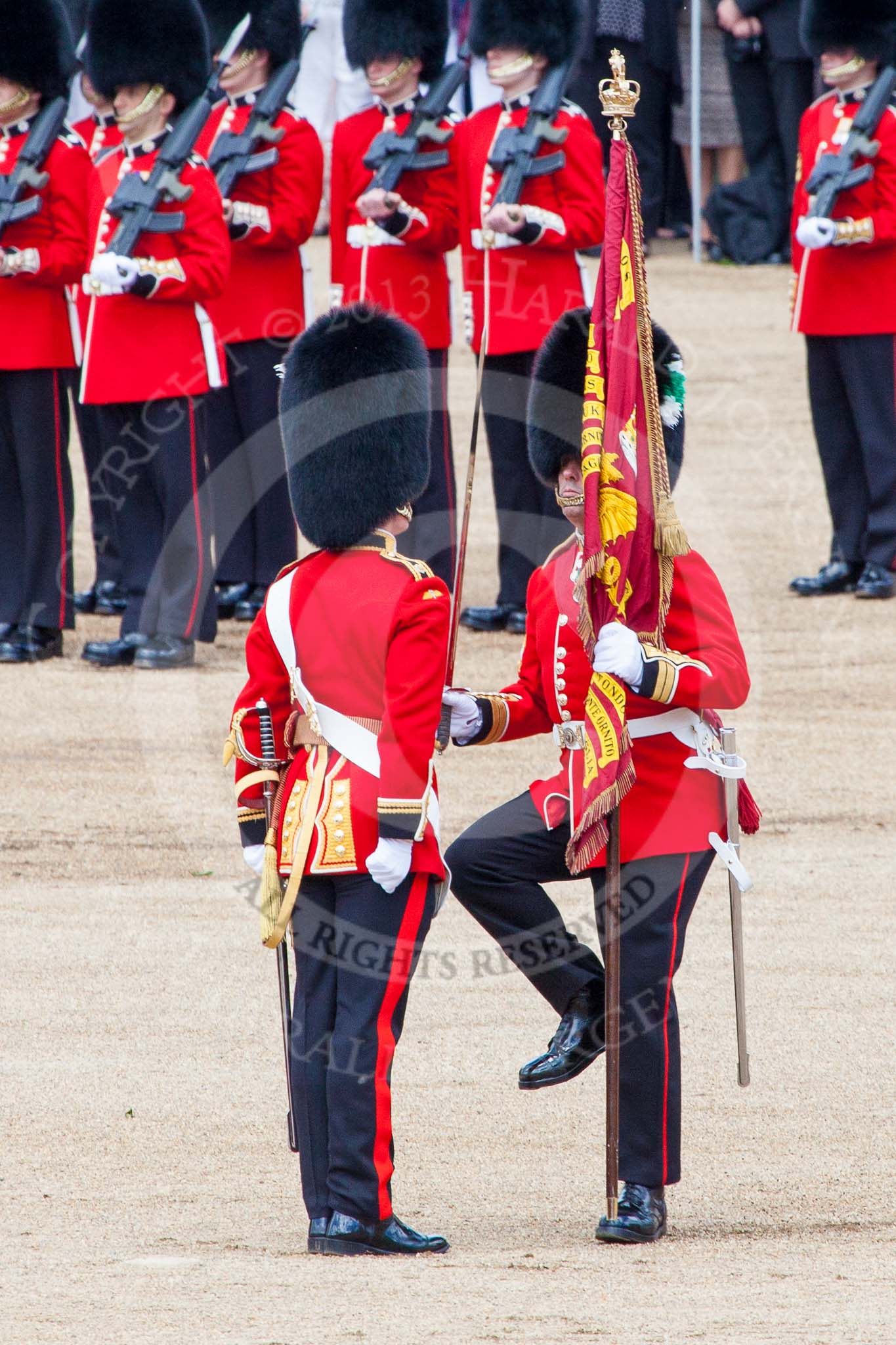 Trooping the Colour 2013: The Colour has been handed over from Colour Sergeant R J Heath, Welsh Guard to the Regimental Sergeant Major, WO1 Martin Topps, Welsh Guards. He now presents the Colour to the Ensign, Ensign, Second Lieutenant Joel Dinwiddle, who salutes the Colour with his sword. Image #454, 15 June 2013 11:21 Horse Guards Parade, London, UK