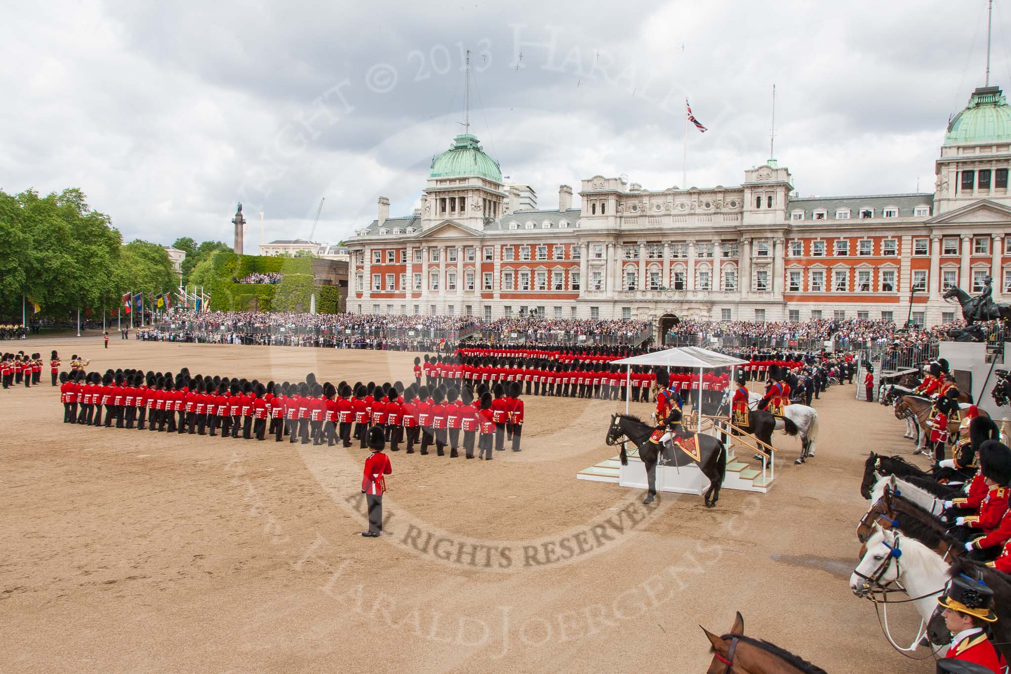 Trooping the Colour 2013: A wide angle overview of Horse Guards Parade during the March Past, with the Royal Colonels on both sides of the dais where HRH The Duke of Kent and HM The Queen are watching the March Past. Image #555, 15 June 2013 11:38 Horse Guards Parade, London, UK