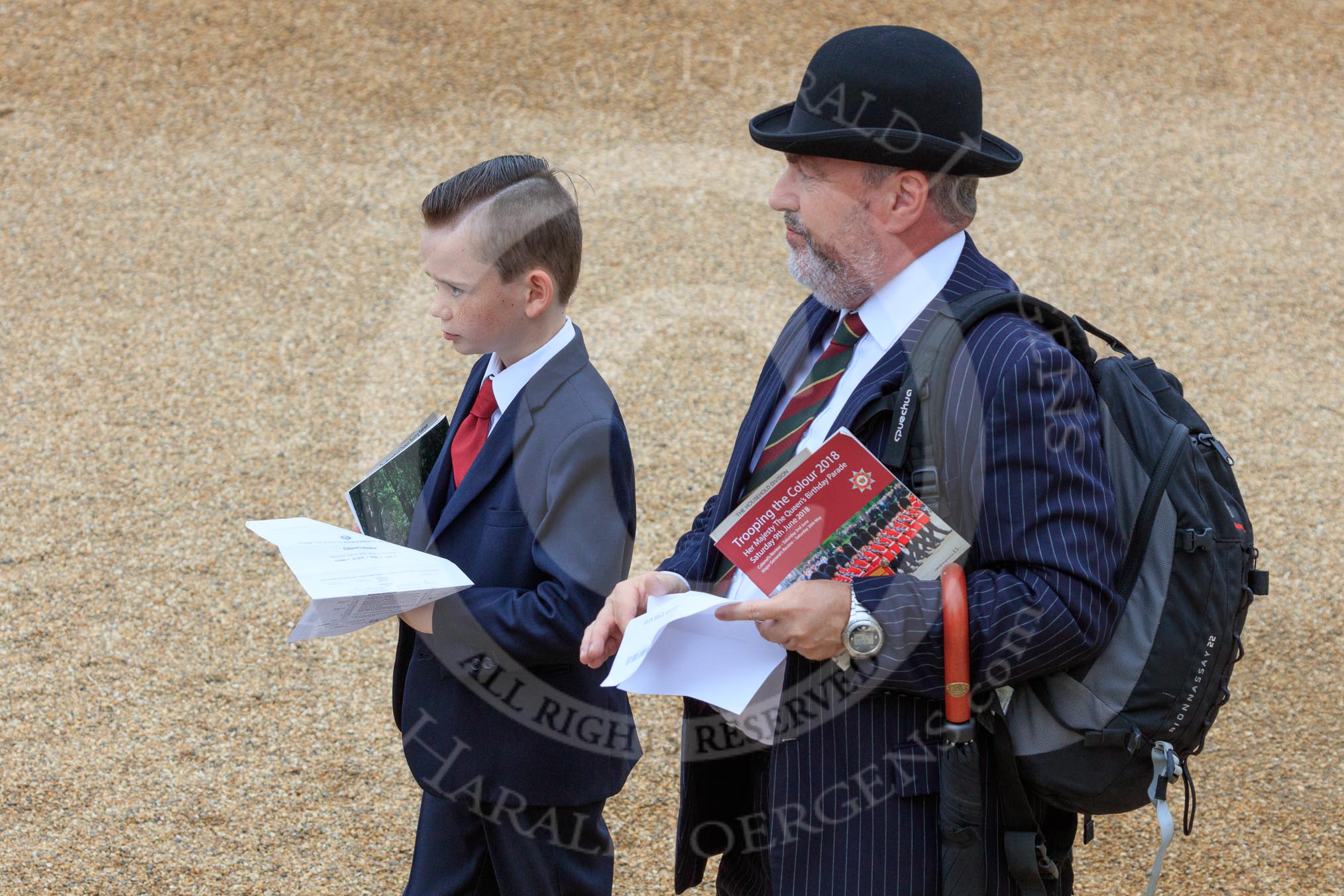 Father and son, both in dark suits, and the father with a Household Division tie, holding their printed tickets and an event programme before The Colonel's Review 2018 (final rehearsal for Trooping the Colour, The Queen's Birthday Parade)  at Horse Guards Parade, Westminster, London, 2 June 2018, 09:19.