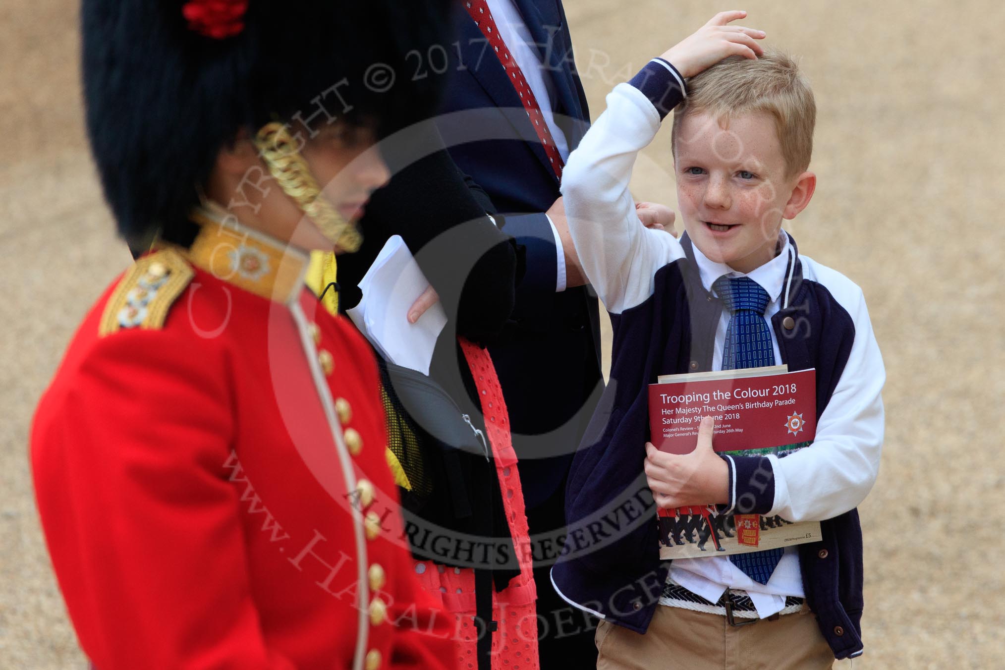Young boy carrying an event programme and looking up to a Captain of the Coldstream Guards before The Colonel's Review 2018 (final rehearsal for Trooping the Colour, The Queen's Birthday Parade)  at Horse Guards Parade, Westminster, London, 2 June 2018, 09:46.