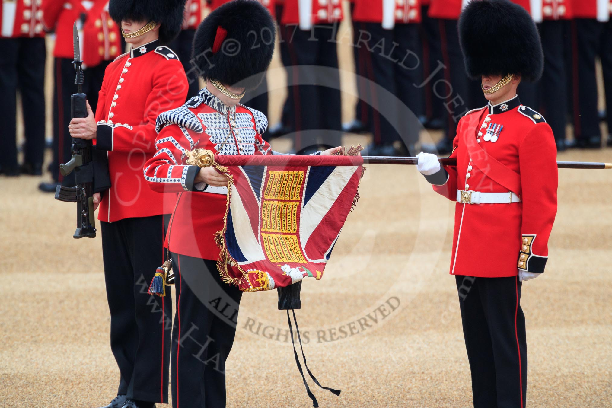Duty Drummer  Sam Orchard uncasing the Colour held by Colour Sergeant Sam McAuley (31), with Colour Sentry Guardsman Jonathon Hughes (26) behind, during The Colonel's Review 2018 (final rehearsal for Trooping the Colour, The Queen's Birthday Parade)  at Horse Guards Parade, Westminster, London, 2 June 2018, 10:33.