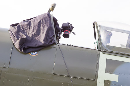 The photo shows the Spitfire cockpit area from the side, with the camera for the panoramic photography. The windscreen is covered by black tarpaulin to shield against the low morning sun.