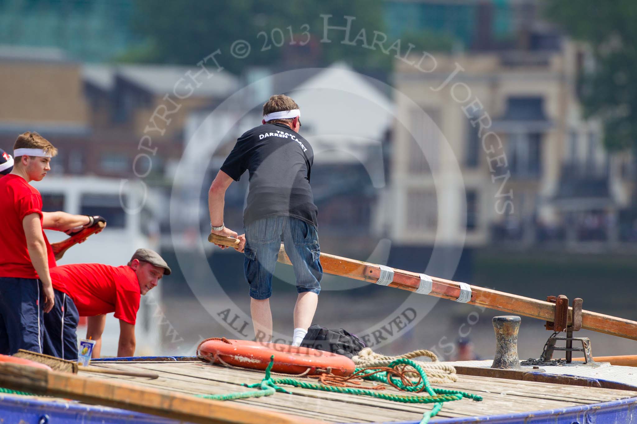 TOW River Thames Barge Driving Race 2013: Rowers on the deck of barge "Spirit of Mountabatten", by Mechanical Movements and Enabling Services Ltd, seen looking over the deck of barge "Darren Lacey", by Princess Pocahontas, during the race..
River Thames between Greenwich and Westminster,
London,

United Kingdom,
on 13 July 2013 at 12:38, image #143