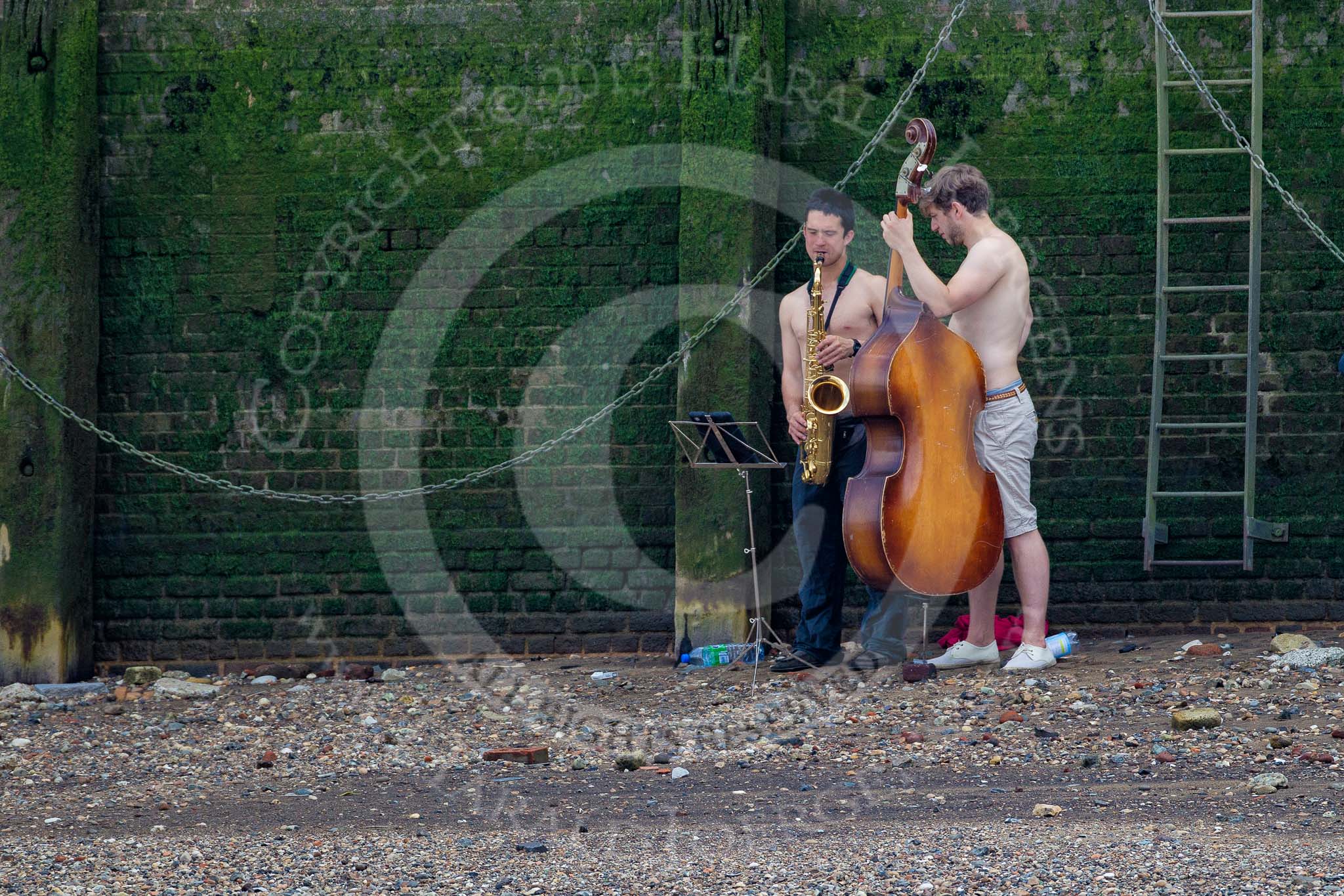 TOW River Thames Barge Driving Race 2013: Two young male musicians playing their instruments by the river..
River Thames between Greenwich and Westminster,
London,

United Kingdom,
on 13 July 2013 at 13:32, image #353