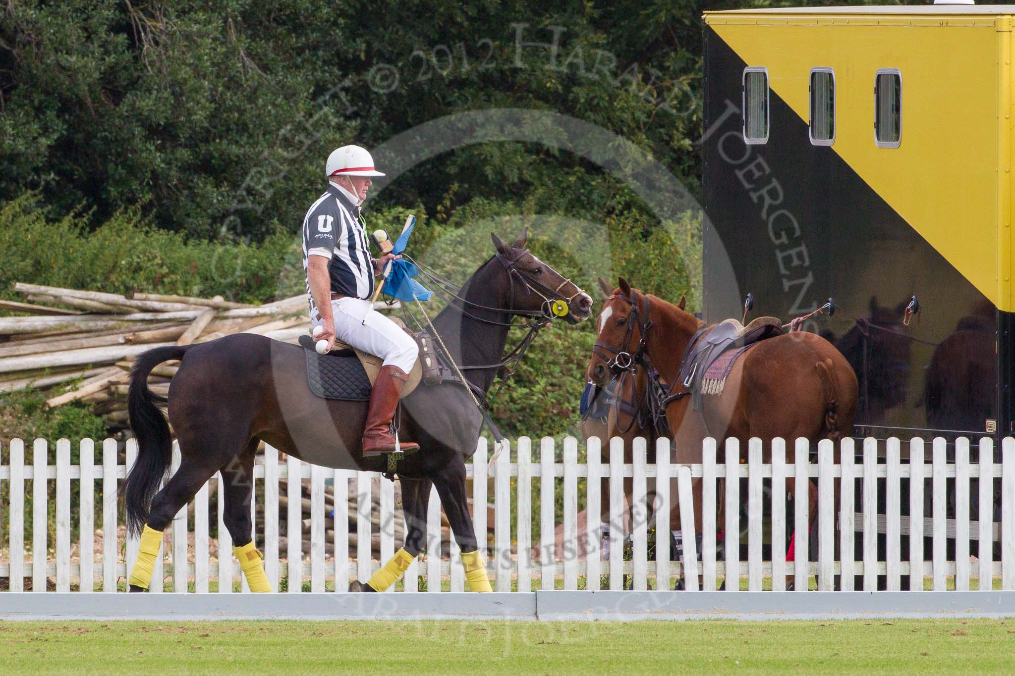 DBPC Polo in the Park 2012: The umpire and club polo manager Ian 'Ginger' Hunt, riding along the pony line with the blue goal flags..
Dallas Burston Polo Club,
Stoneythorpe Estate,
Southam,
Warwickshire,
United Kingdom,
on 16 September 2012 at 10:01, image #22