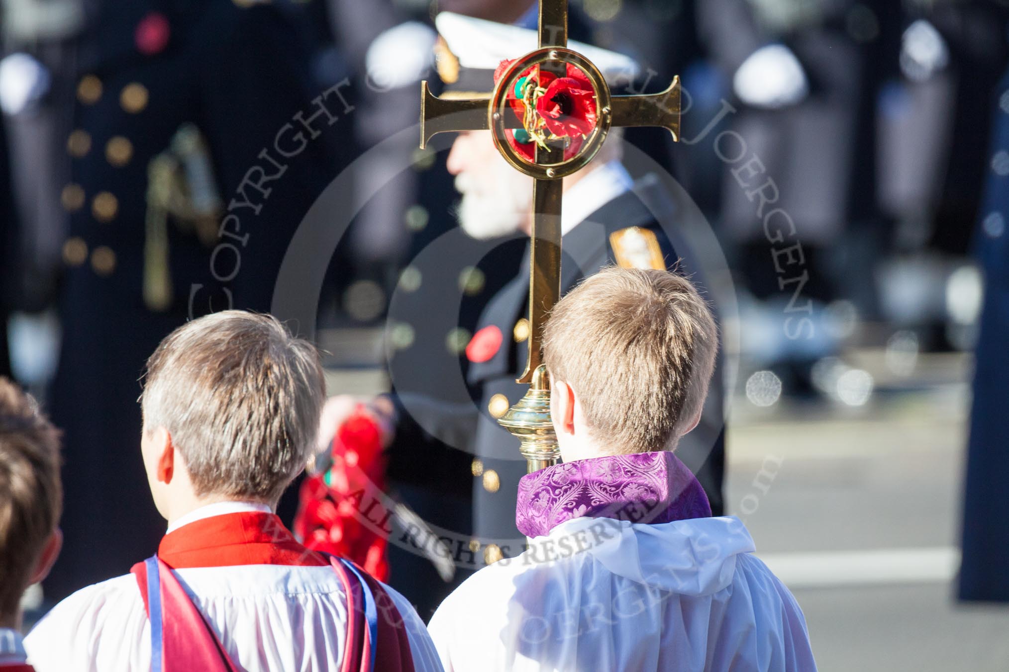 HRH Prince Michael of Kent about to lay his wreath at the Cenotaph. He is out of focus behind the golden cross with the red poppies held by the cross bearer.