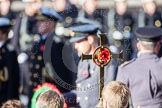 The golden cross with the poppies, held by the cross bearer, behind it, and out of focus, HRH The Duke of Cambridge.