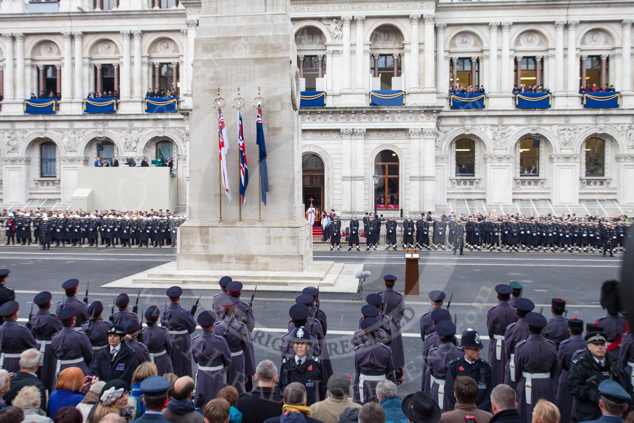 Remembrance Sunday at the Cenotaph in London 2014: The Cenotaph just before the start of the event, the Cross Bearer is leaving the Foreign- and Commonwealth Office.
Press stand opposite the Foreign Office building, Whitehall, London SW1,
London,
Greater London,
United Kingdom,
on 09 November 2014 at 10:53, image #95