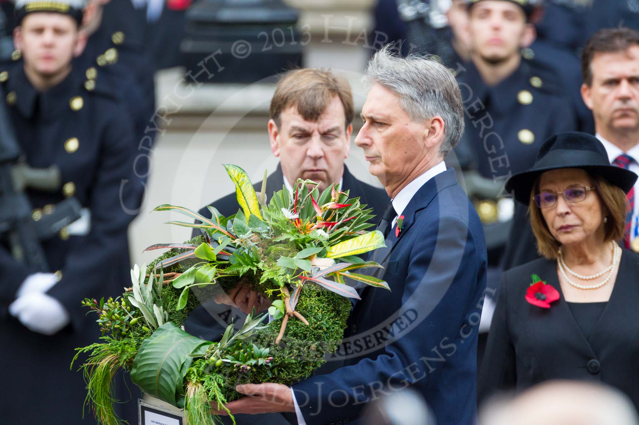 Remembrance Sunday at the Cenotaph 2015: The Secretary of State for Foreign and Commonwealth Affairs, Philip Hammond, walking toward the Cenotaph with his wreath on behalf of 14 overseas terretories. The wreath is made of flowers from all 14 terretories. Image #222, 08 November 2015 11:08 Whitehall, London, UK