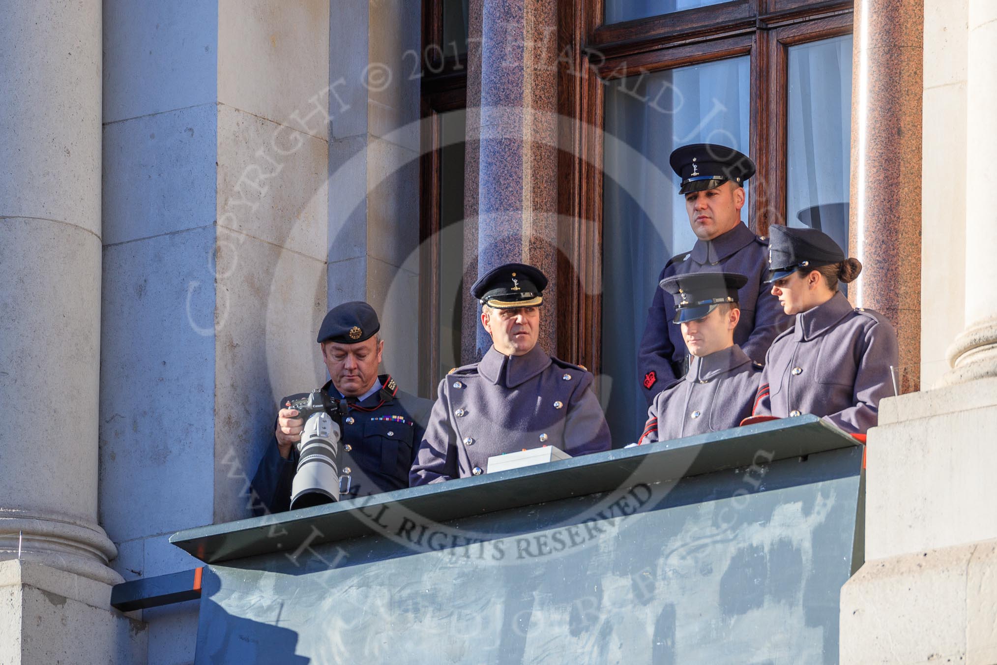 Army officers and an army photographer in one of the top floor windows of the Foreign and Commonwealth Office before the Remembrance Sunday Cenotaph Ceremony 2018 at Horse Guards Parade, Westminster, London, 11 November 2018, 09:52. I believe they control all or parts of the event - if you know more, please let me know!