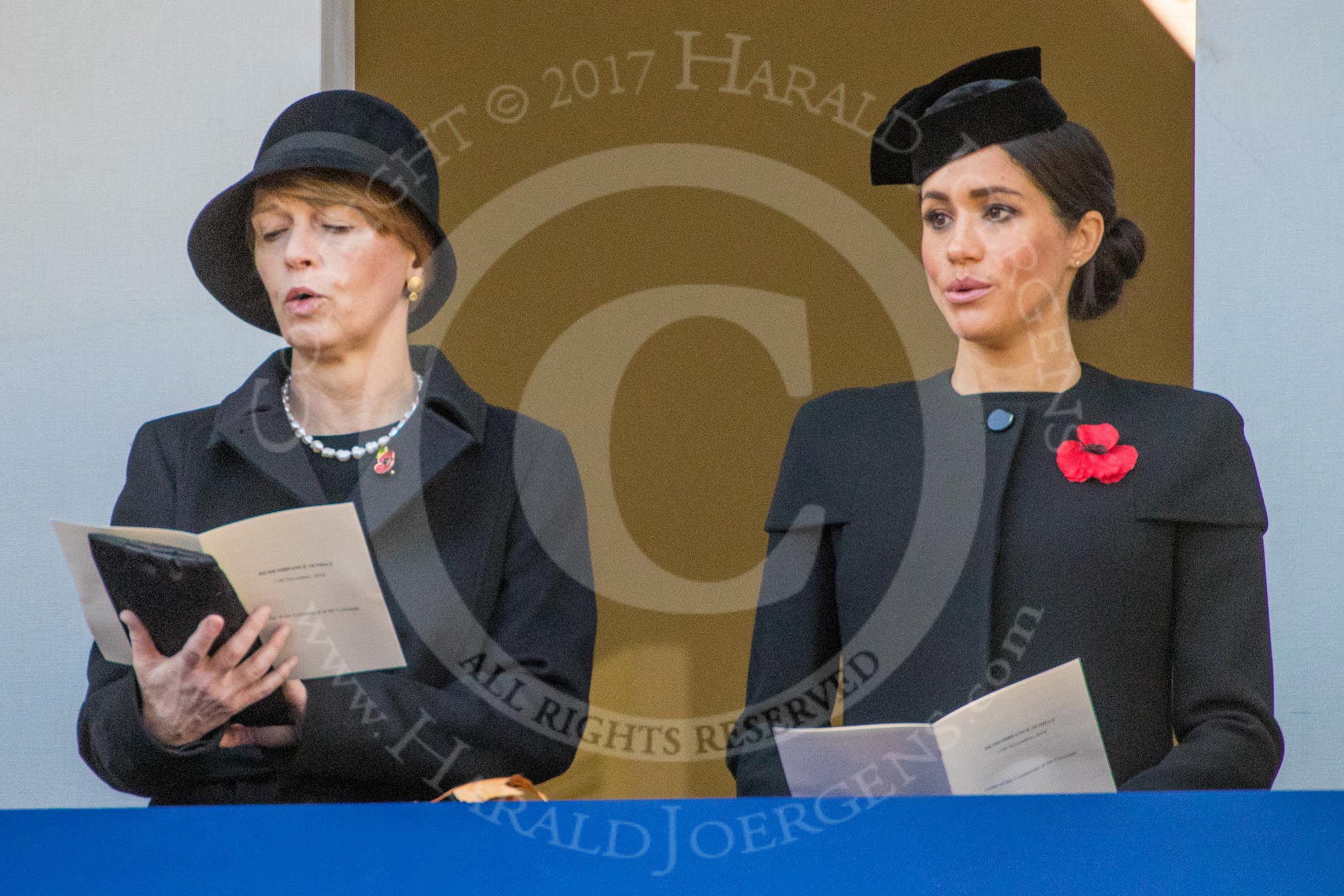Mrs. Elke Büdenbender, wife of HE The President of the Federal Republic of Germany, Frank-Walter Steinmeier and HRH The Duchess of Sussex (Meghan), singing, on the balcony of the Foreign and Commonwealth Office during the Remembrance Sunday Cenotaph Ceremony 2018 at Horse Guards Parade, Westminster, London, 11 November 2018, 11:19.