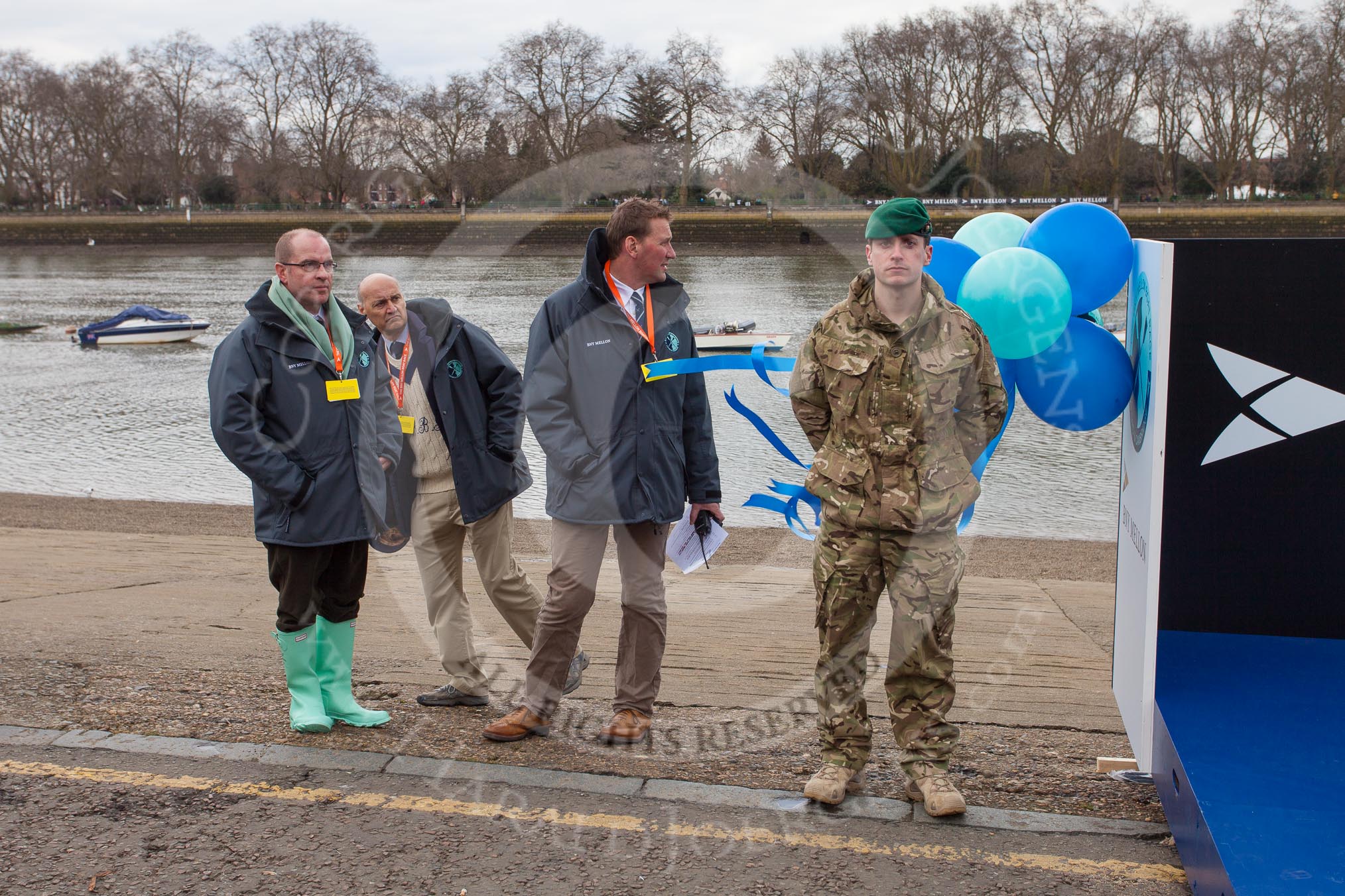 The Boat Race 2013: Minutes before the toss of the coin - a member of the BBC production team, umpire Boris Rankov, in charge of the Isis/Goldie race toss, umpire Sir Matthew Pinsent, in charge of the Blue Boat toss, and a Royal Marine guarding the trophy..
Putney,
London SW15,

United Kingdom,
on 31 March 2013 at 14:22, image #74
