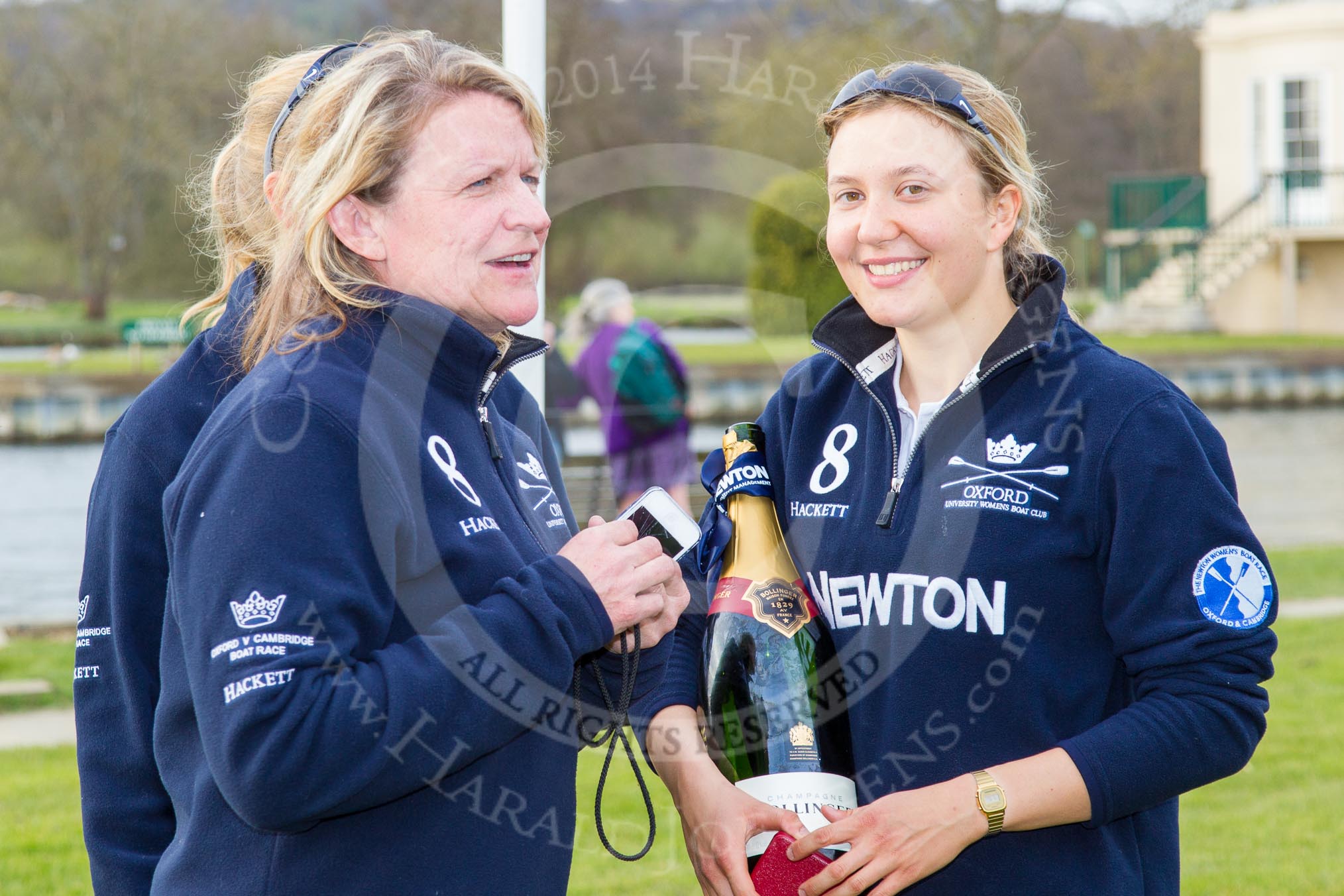 The Women's Boat Race and Henley Boat Races 2014: Christine Wilson, OUWBC Chief Coach, with OUWBC president Maxie Scheske and a bottle of Bollinger Champagne..
River Thames,
Henley-on-Thames,
Buckinghamshire,
United Kingdom,
on 30 March 2014 at 17:15, image #539