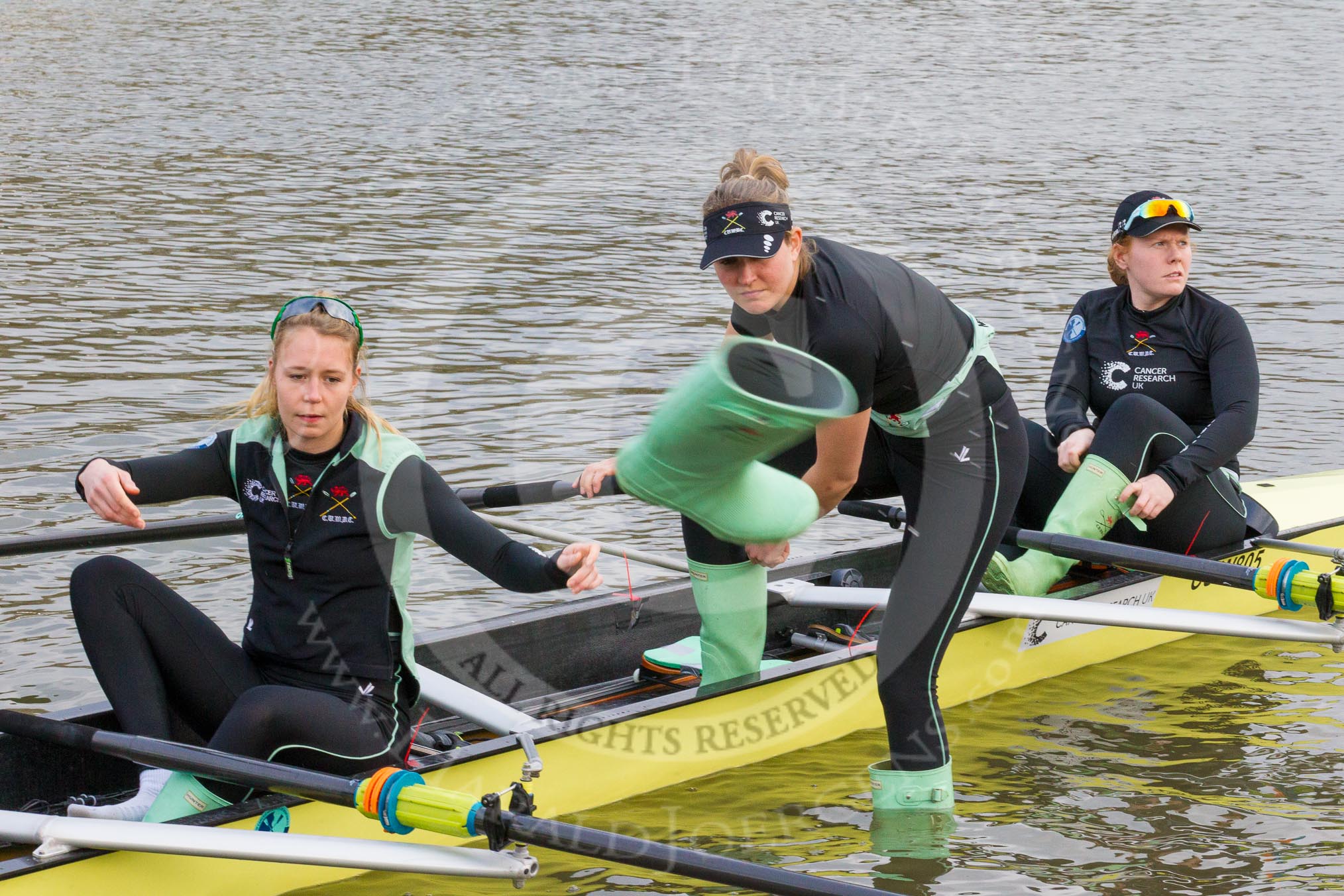 The Boat Race season 2017 - Women's Boat Race Fixture CUWBC vs Univerity of London: CUWBC's 3, Ashton Brown, 2 Kirsten van Fosen, and bow Claire Lamb getting rid of their Wellies.
River Thames between Putney Bridge and Mortlake,
London SW15,

United Kingdom,
on 19 February 2017 at 15:16, image #10