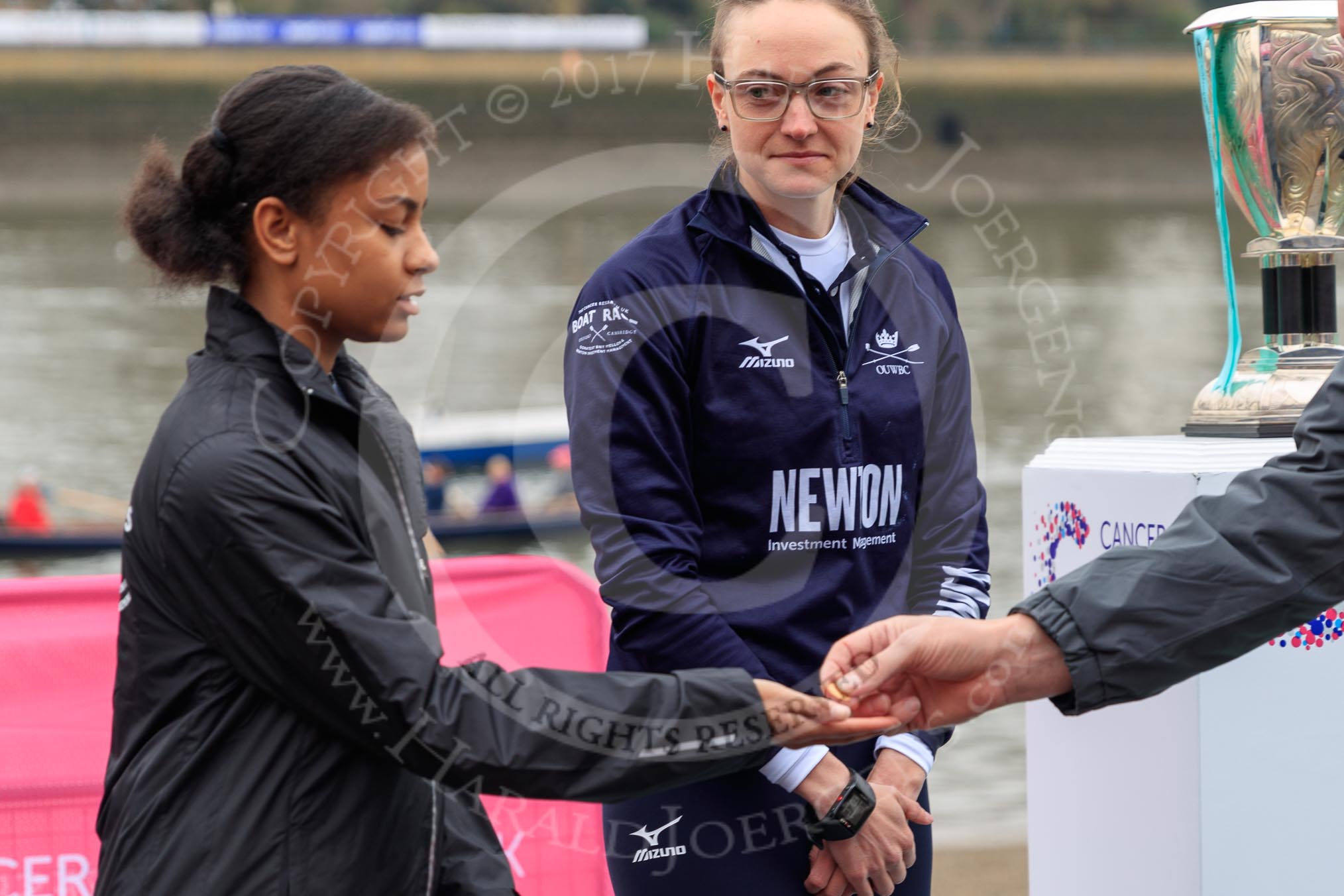 The Cancer Research UK Women's Boat Race 2018: Zahara Alacia, a 15 years old member of the Boat Race Future Blues Programme, receiving the coin for the toss. Behind her OUWBC president Katherine Erickson.
River Thames between Putney Bridge and Mortlake,
London SW15,

United Kingdom,
on 24 March 2018 at 14:40, image #42