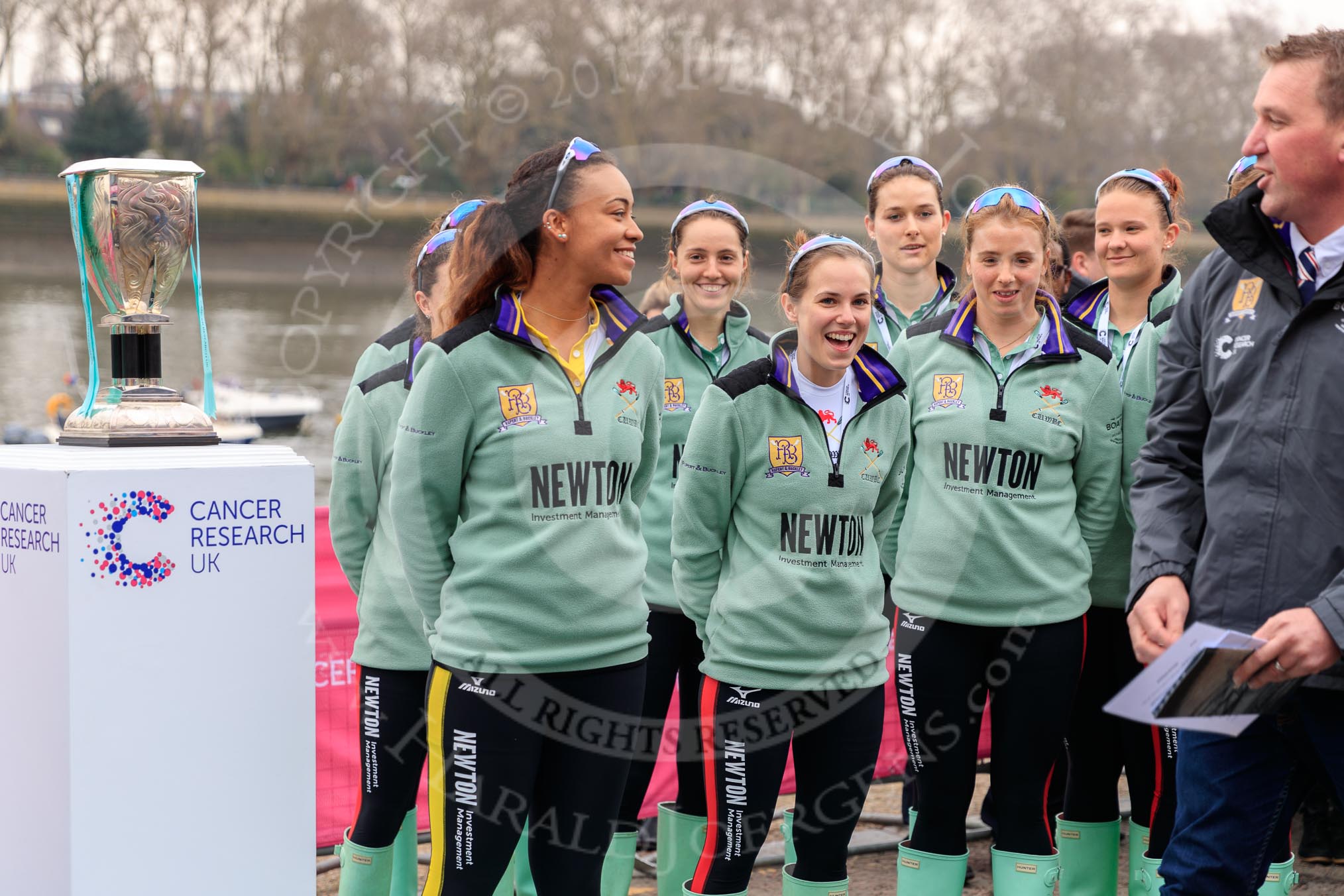 The Cancer Research UK Women's Boat Race 2018: The Cambridge crew with the Women's Boat Race trophy at the toss - president Daphne Martschenko (rowing in the reserve boat), cox Sophie Shapter, 6 Alice White, 7 Myriam Goudet-Boukhatmi, and in the second row 2 seat Imogen Grant, 3 Kelsey Barolak, 4 Thea Zabell, and 5 Paula Wesselmann. On the right race umpire Sir Matthew Pinsent..
River Thames between Putney Bridge and Mortlake,
London SW15,

United Kingdom,
on 24 March 2018 at 14:41, image #47