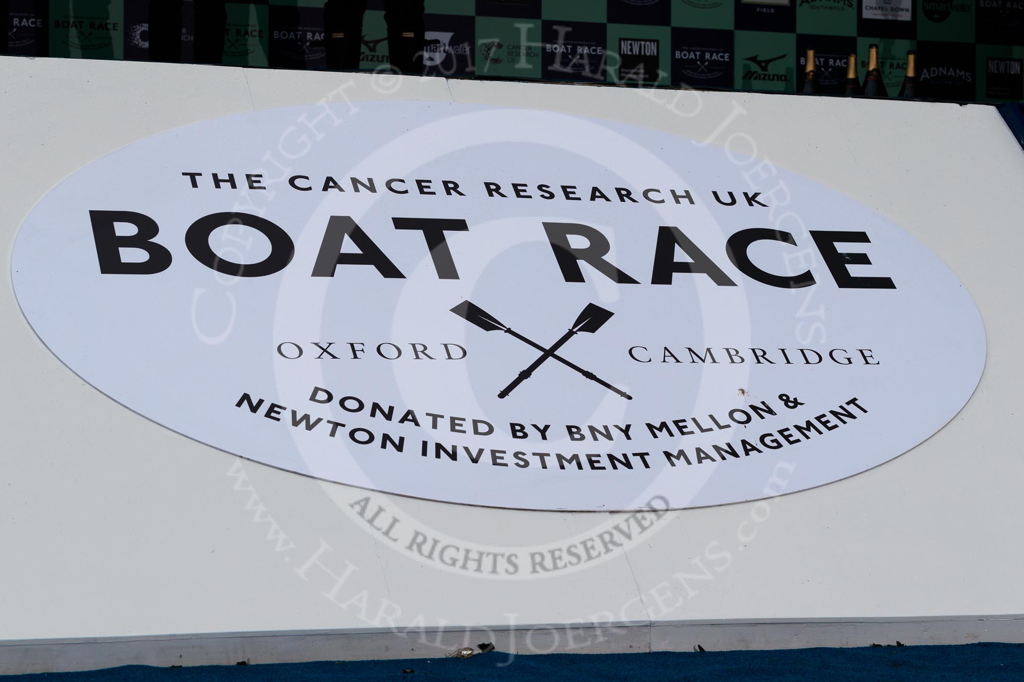 The Cancer Research UK Women's Boat Race 2018: The big sign at the podium for the Booat Race trophy presentation - "The Cancer Research UK Boat Race".
River Thames between Putney Bridge and Mortlake,
London SW15,

United Kingdom,
on 24 March 2018 at 17:05, image #235