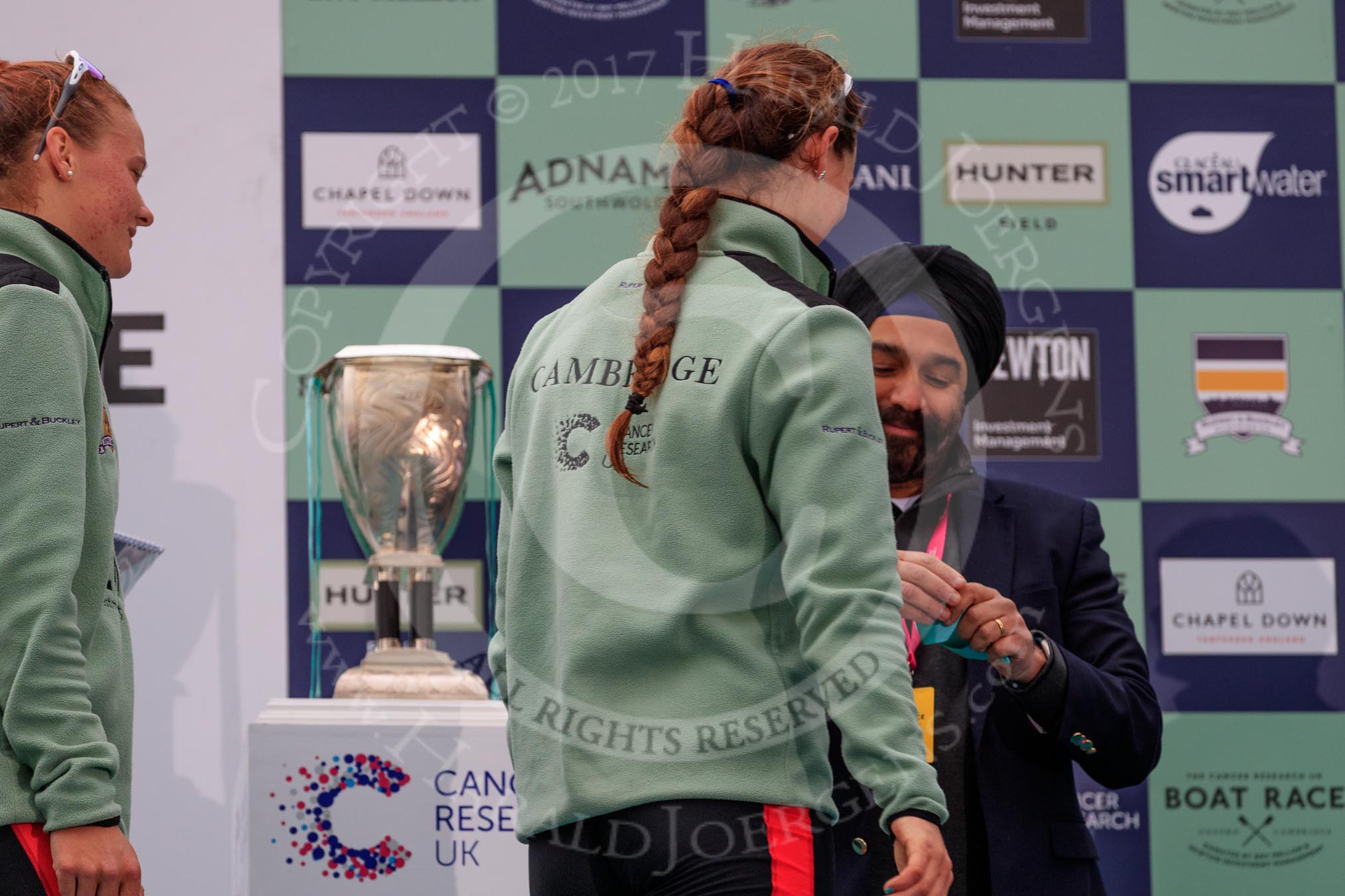 The Cancer Research UK Women's Boat Race 2018: Sir Harpal Kumar, CEO of Cancer Research UK. congratulating Cambridge 3 seat Kelsey Barolak at the trophy presentation.
River Thames between Putney Bridge and Mortlake,
London SW15,

United Kingdom,
on 24 March 2018 at 17:06, image #257
