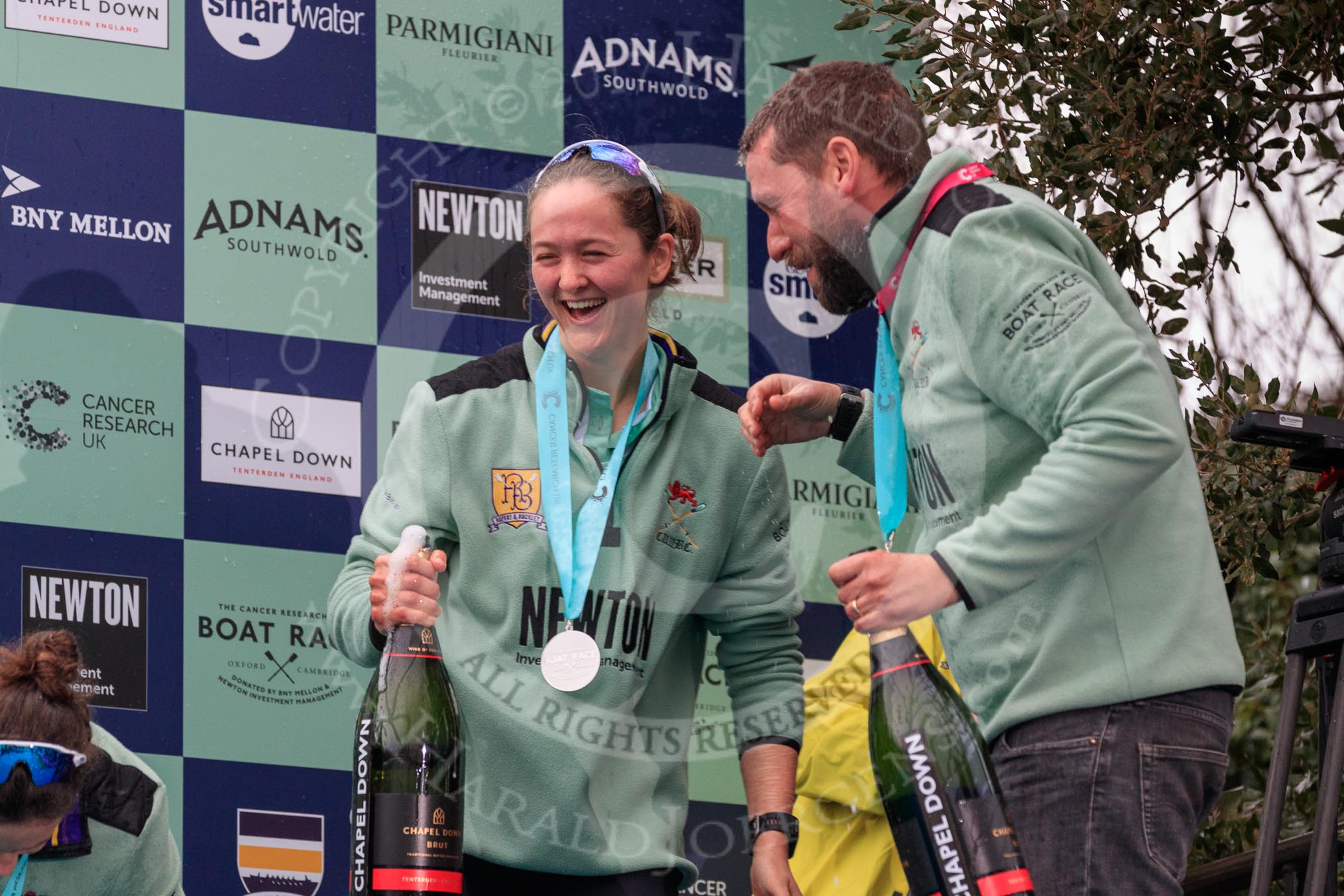 The Cancer Research UK Women's Boat Race 2018: Cambridge bow Tricia Smith, CUWBC Head Coach Rob Baker, Boat Race medals, and bottles of Chapel Down Brut.
River Thames between Putney Bridge and Mortlake,
London SW15,

United Kingdom,
on 24 March 2018 at 17:09, image #287