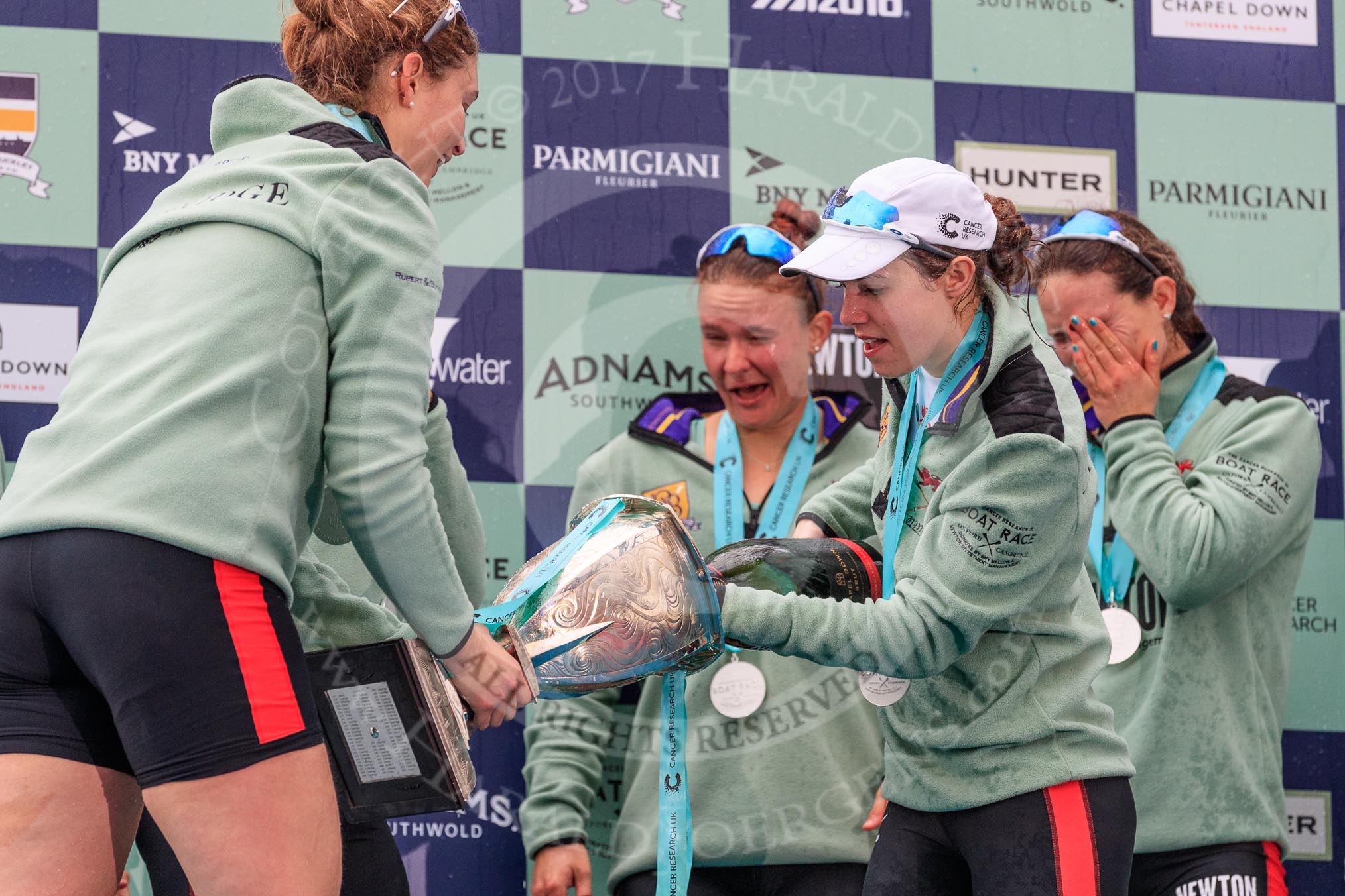 The Cancer Research UK Women's Boat Race 2018: Cambridge 7 seat Myriam Goudet-Boukhatmi ho;ding the Women's Boat Race trophy, and cox Sophie Shapter filling it with champagne.
River Thames between Putney Bridge and Mortlake,
London SW15,

United Kingdom,
on 24 March 2018 at 17:09, image #288