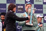 The Cancer Research UK Women's Boat Race 2018: Newton Investment CEO Hanneke Smits handing the Women's Boat Race trophy to Cambridge 7 seat Myriam Goudet-Boukhatmi whilst the first Champagne bottles are opened. On the left, taking cover, Cancer Research CEO Sir Harpal Kumar, on the right Cambridge cox Sophie Shapter.
River Thames between Putney Bridge and Mortlake,
London SW15,

United Kingdom,
on 24 March 2018 at 17:09, image #276