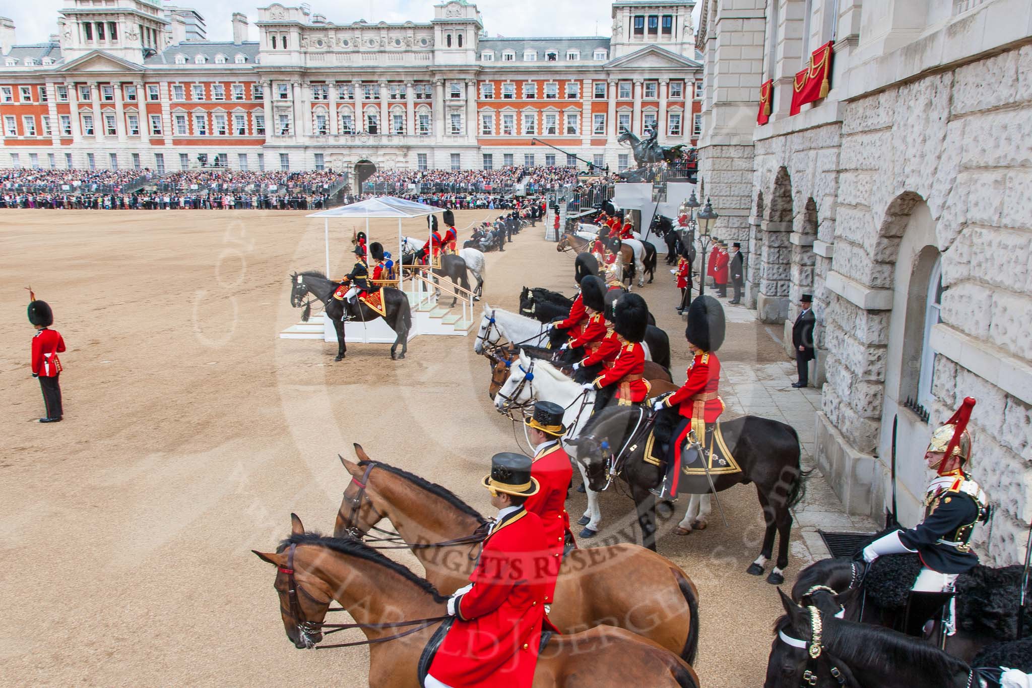 Trooping the Colour 2013: A wide-angle view over the Horse Guards Building side of the parade ground. On the right the windows of the Major General's Office, next to the dais the Royal Colonels, behind them the other members of the Royal Procession,. Image #406, 15 June 2013 11:12 Horse Guards Parade, London, UK
