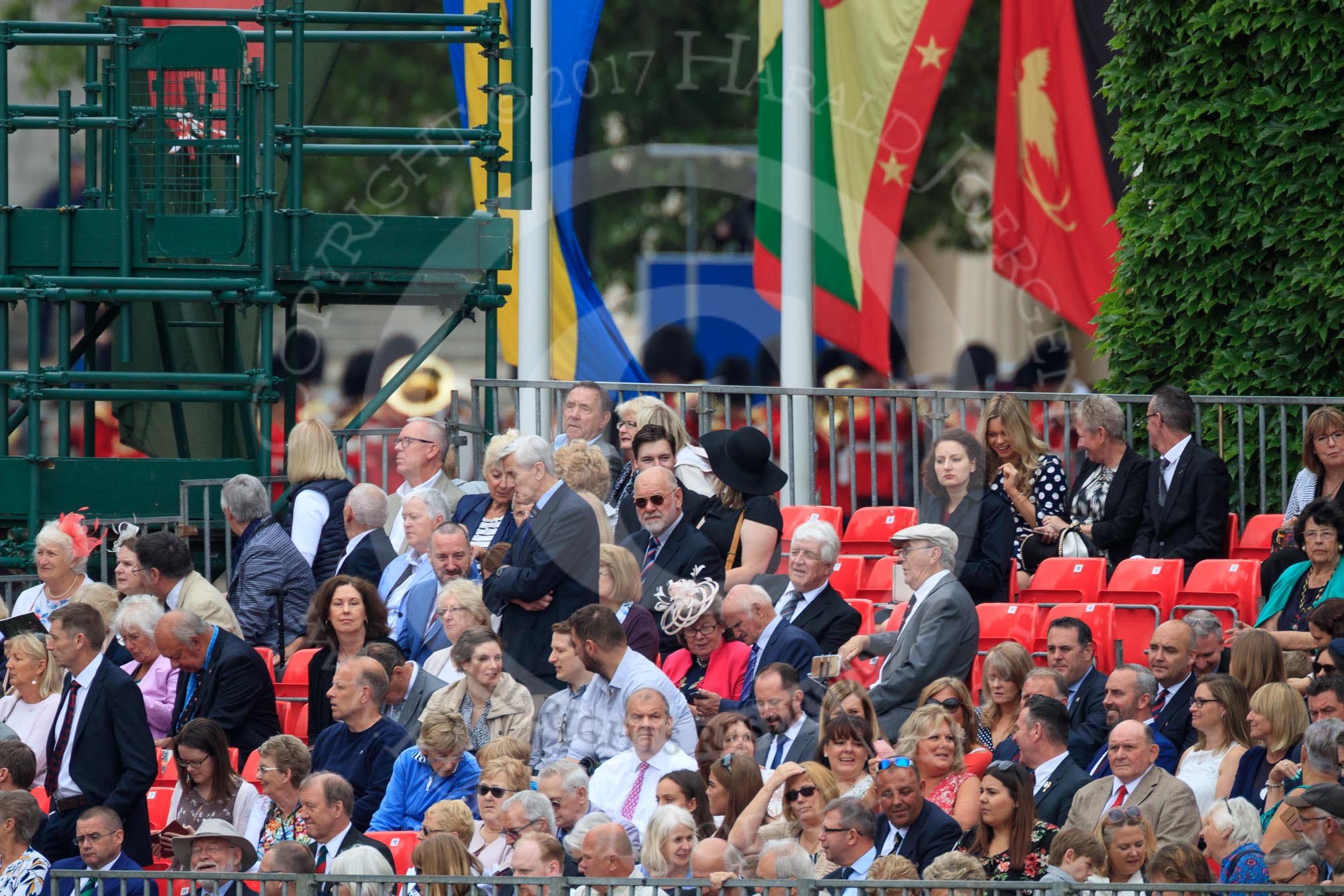 Spectators on the A grandstand, with the Band of the Welsh Guards in the background, turning from The Mall to Horse Guards Parade during The Colonel's Review 2018 (final rehearsal for Trooping the Colour, The Queen's Birthday Parade)  at Horse Guards Parade, Westminster, London, 2 June 2018, 10:10.
