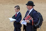 Father and son, both in dark suits, and the father with a Household Division tie, holding their printed tickets and an event programme before The Colonel's Review 2018 (final rehearsal for Trooping the Colour, The Queen's Birthday Parade)  at Horse Guards Parade, Westminster, London, 2 June 2018, 09:19.